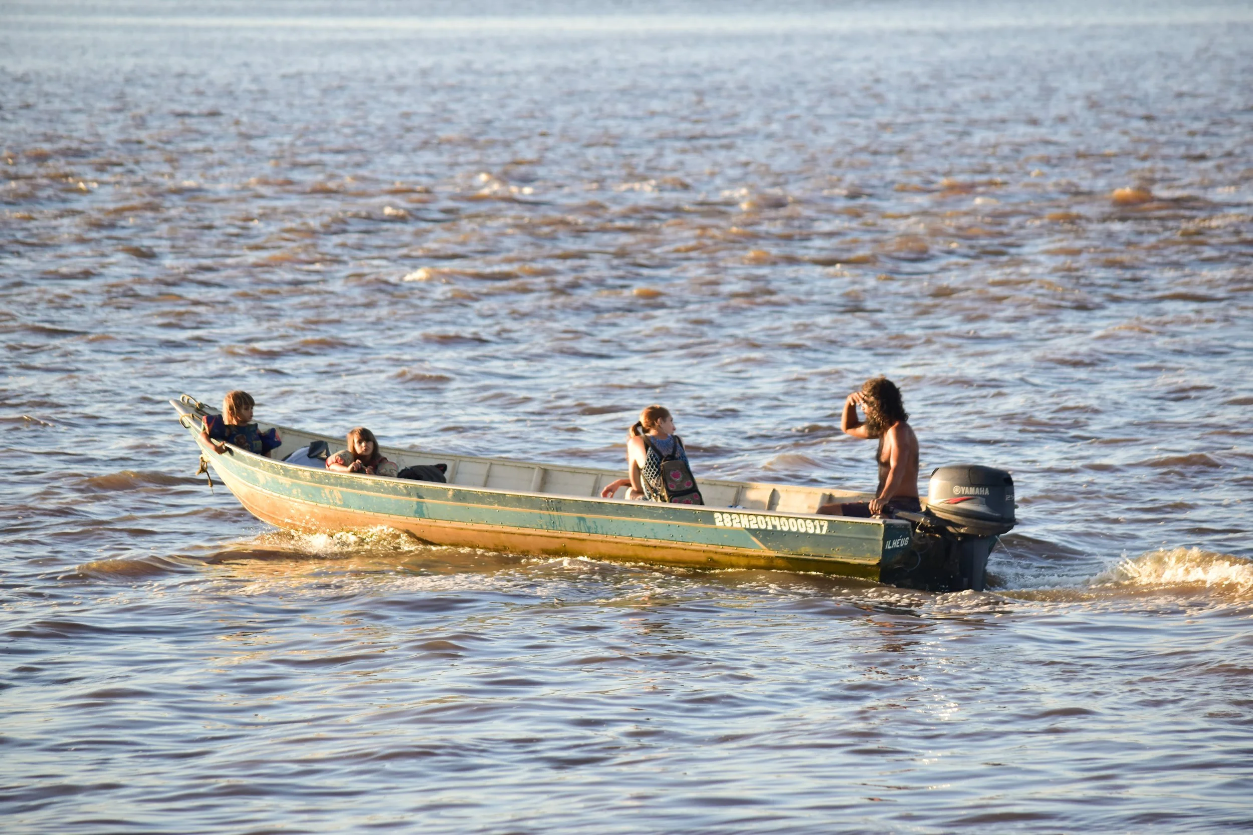 A small boat with four people and an outboard motor moving through water.