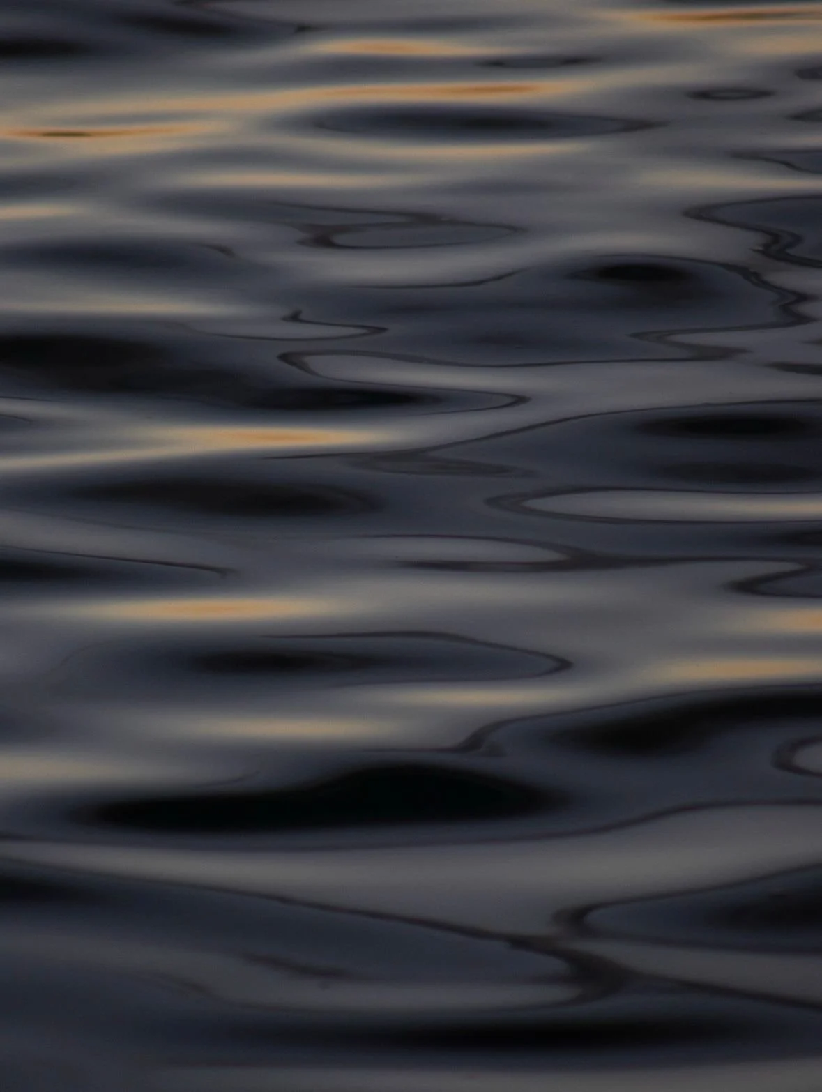 Close-up of dark, rippling water at sunset or sunrise.