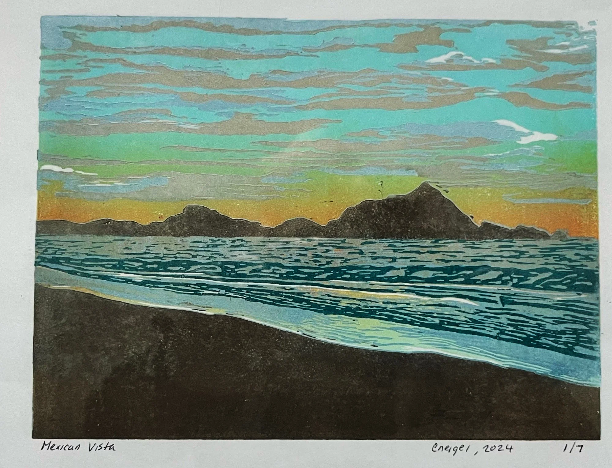 sunset with beach in foreground and landscape in the distance