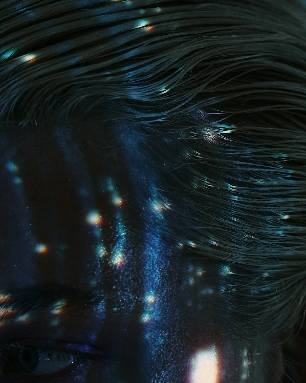 Close-up of a person's face and hair with starry galaxy reflections and light spots magnified.