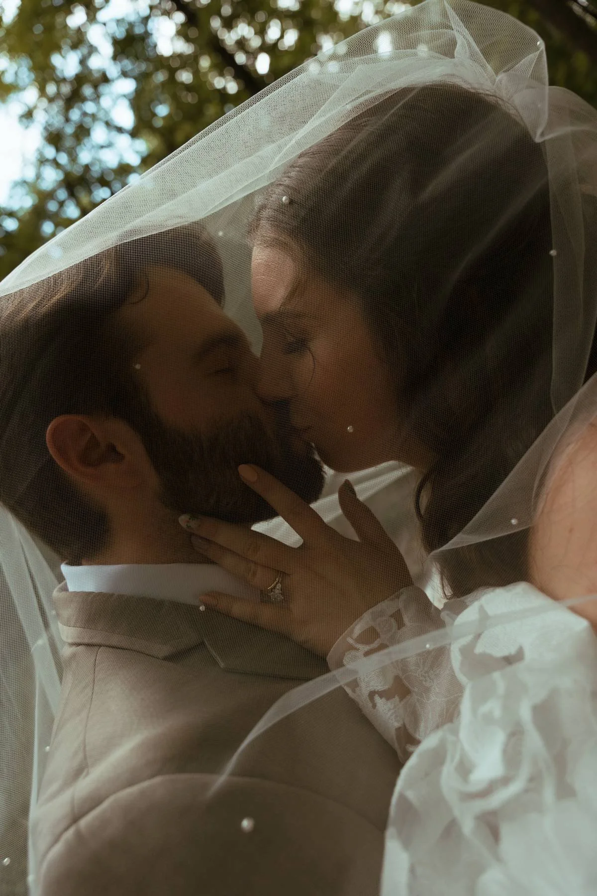 Dark and Moody Bride and Groom kissing underneath a veil at the Thorncrown Chapel in Eureka Springs Arkansas