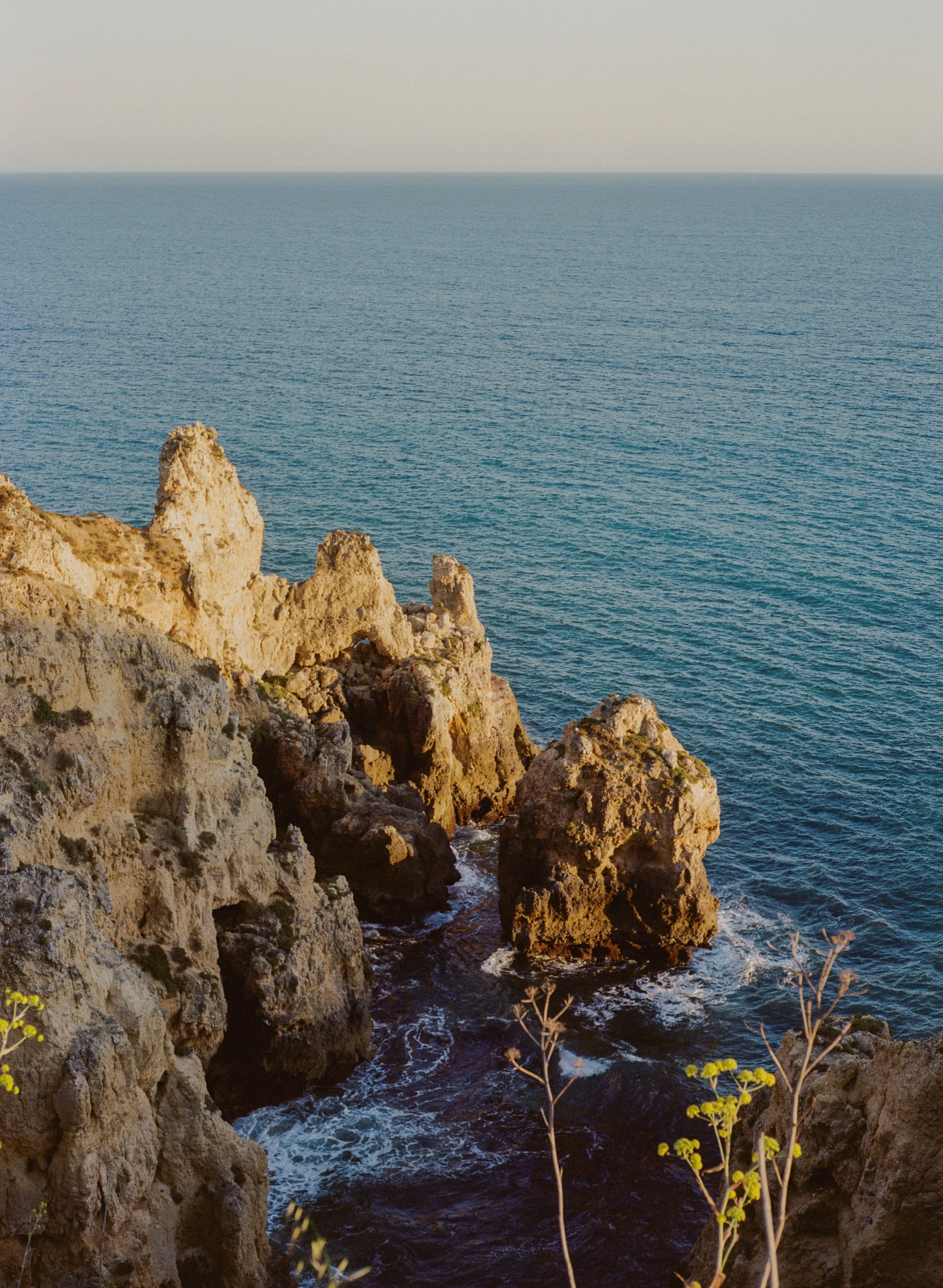 Cliffs along a coastline with the ocean in the background, during sunset.