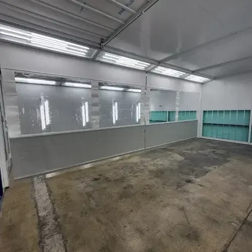 Automotive paint booth interior with airflow floor and lighting for collision repair
