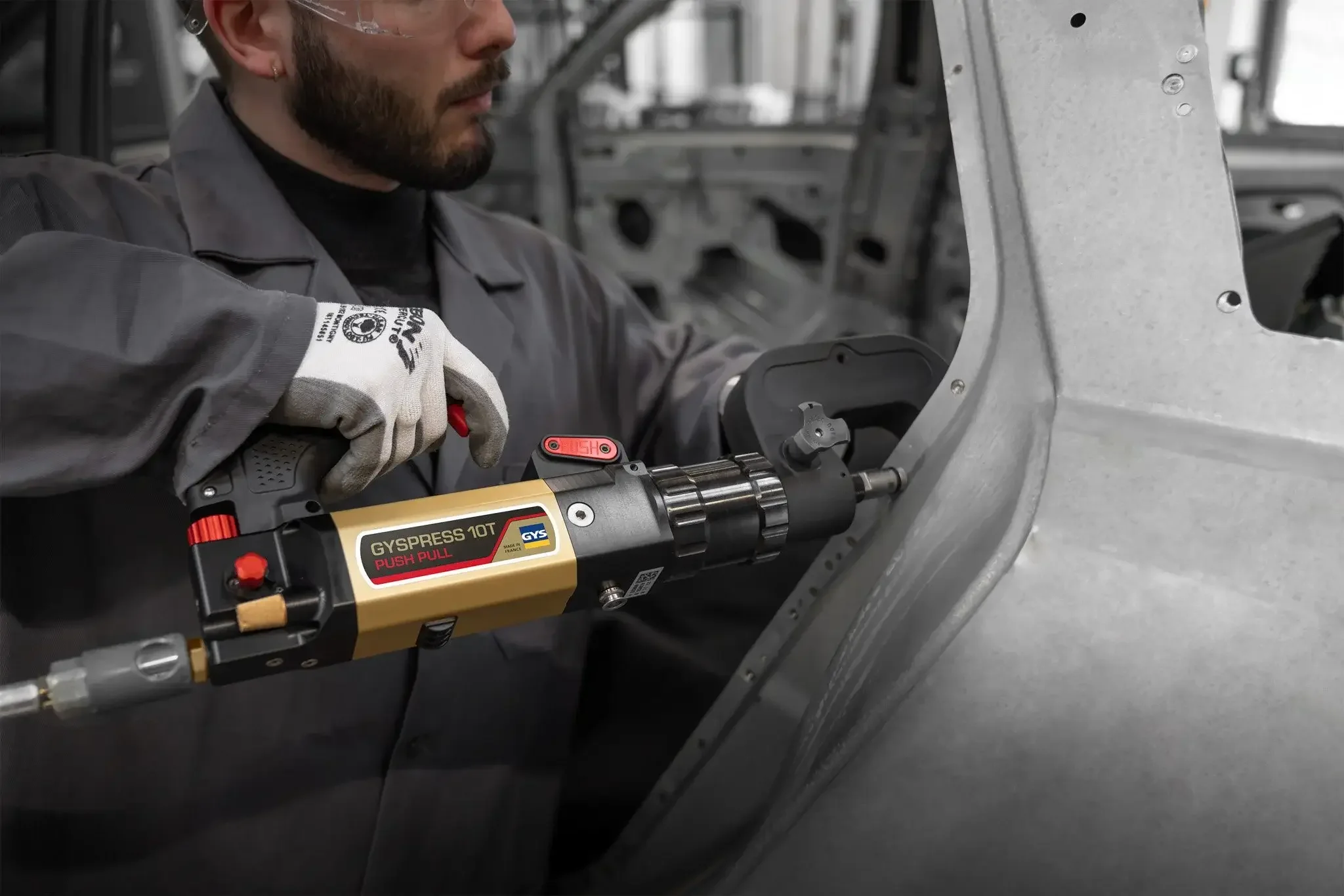Tech using rivet guy on car in a collision repair shop