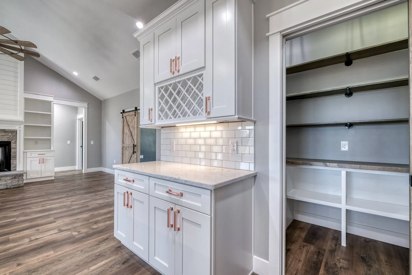 Modern kitchen with white cabinetry, copper handles, white subway tile backsplash, and open shelving on the right.