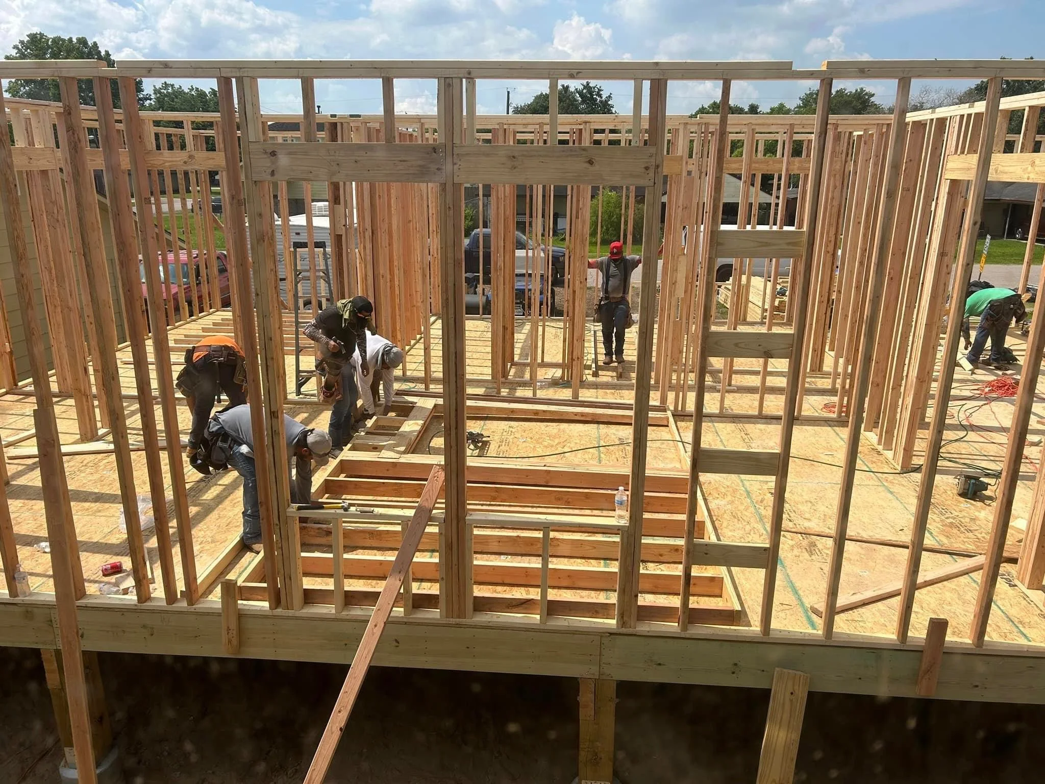 Construction workers assembling the wooden frame of a house on a sunny day.