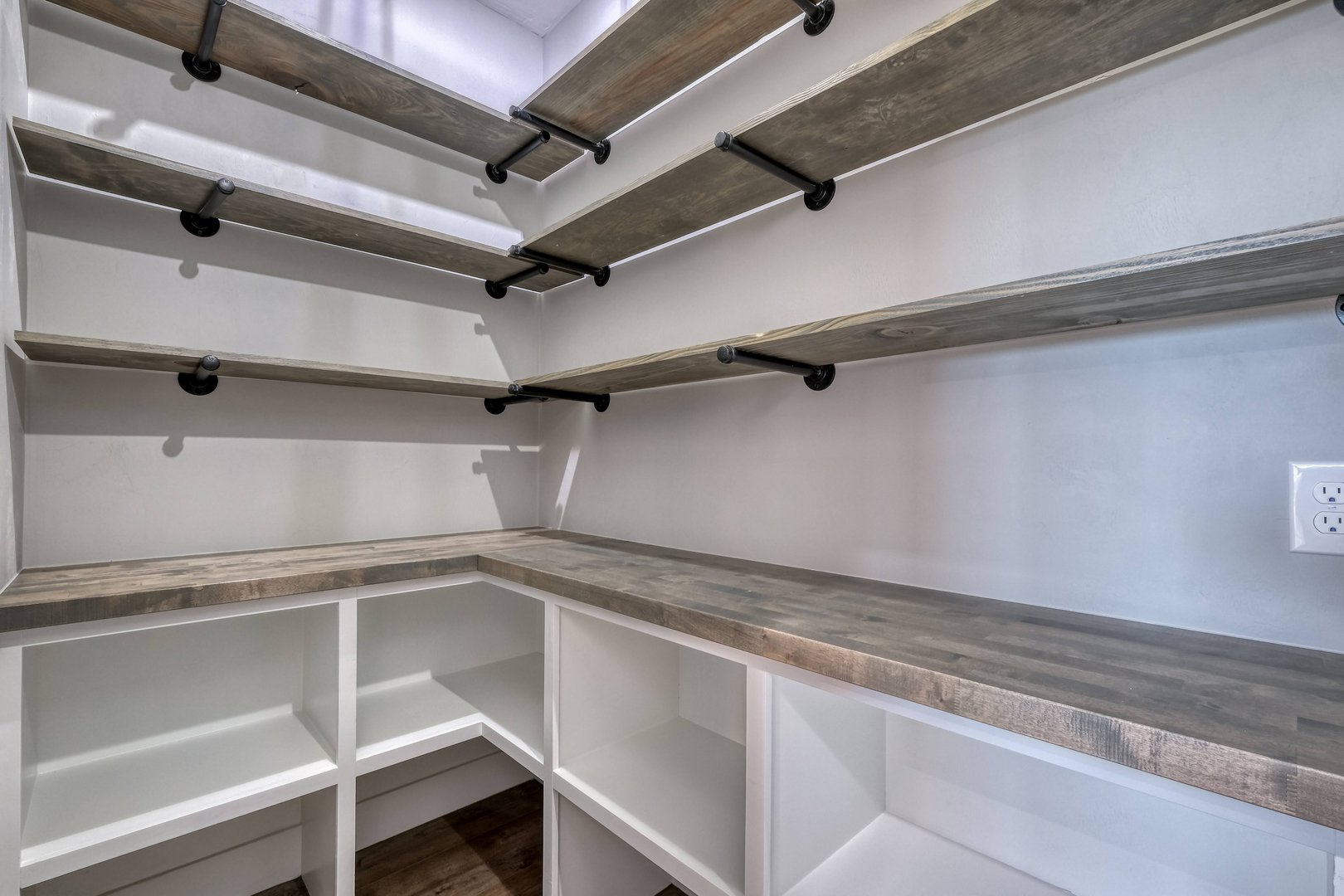 Empty walk-in closet with multiple wood shelves and white cubbies for storage.