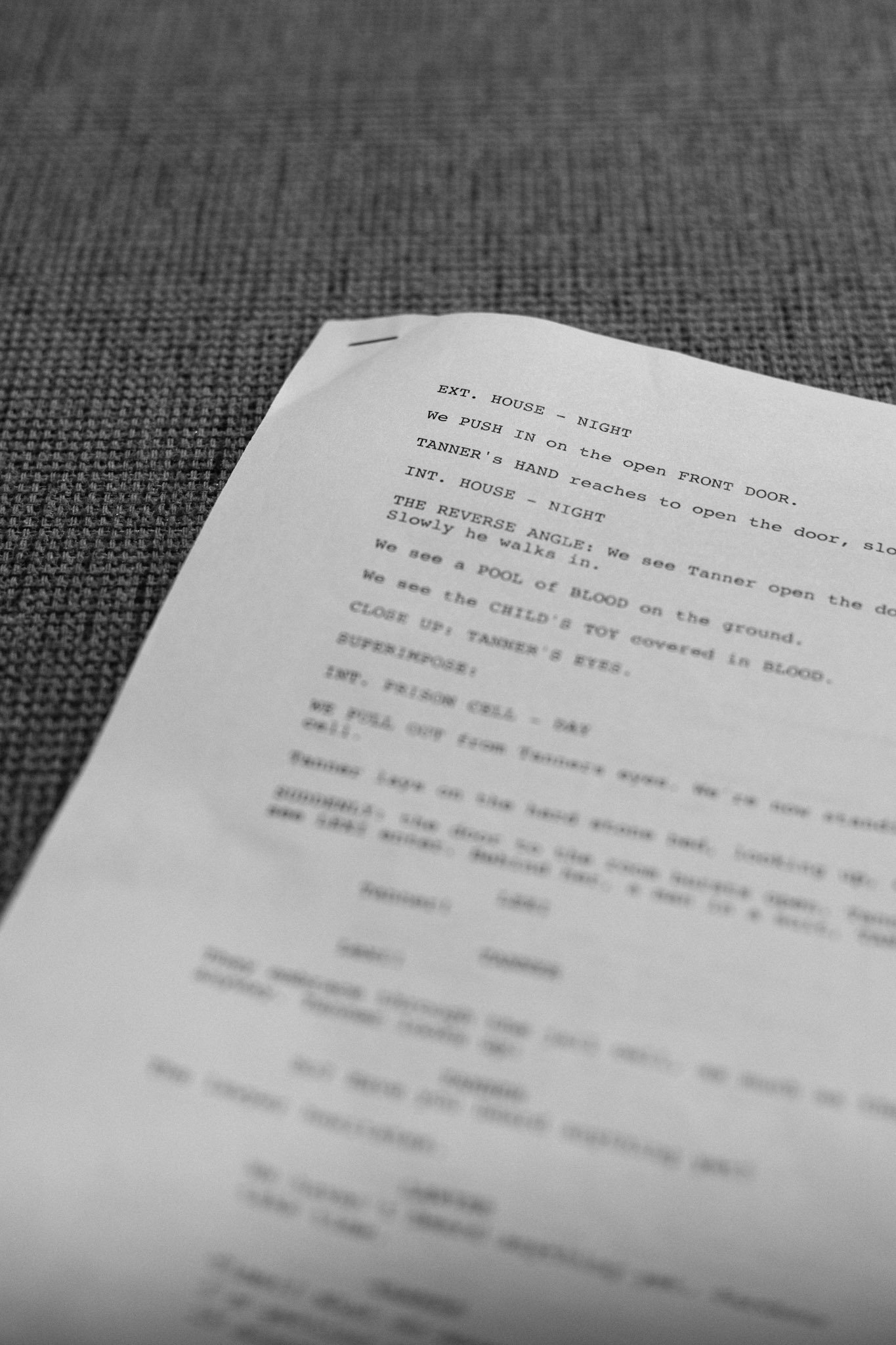 A printed script or screenplay on a piece of paper resting on a textured gray surface.
