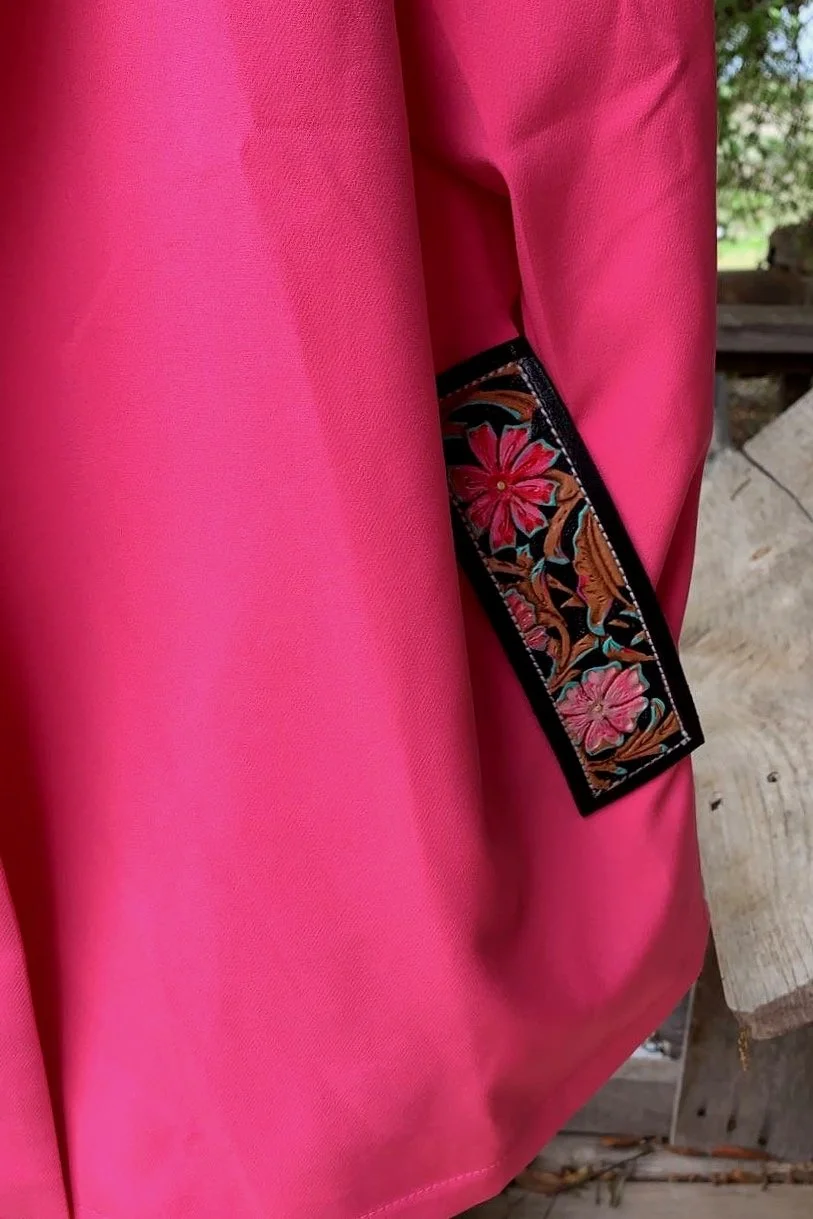 Close-up of a pink fabric garment with an embroidered floral patch on the sleeve.