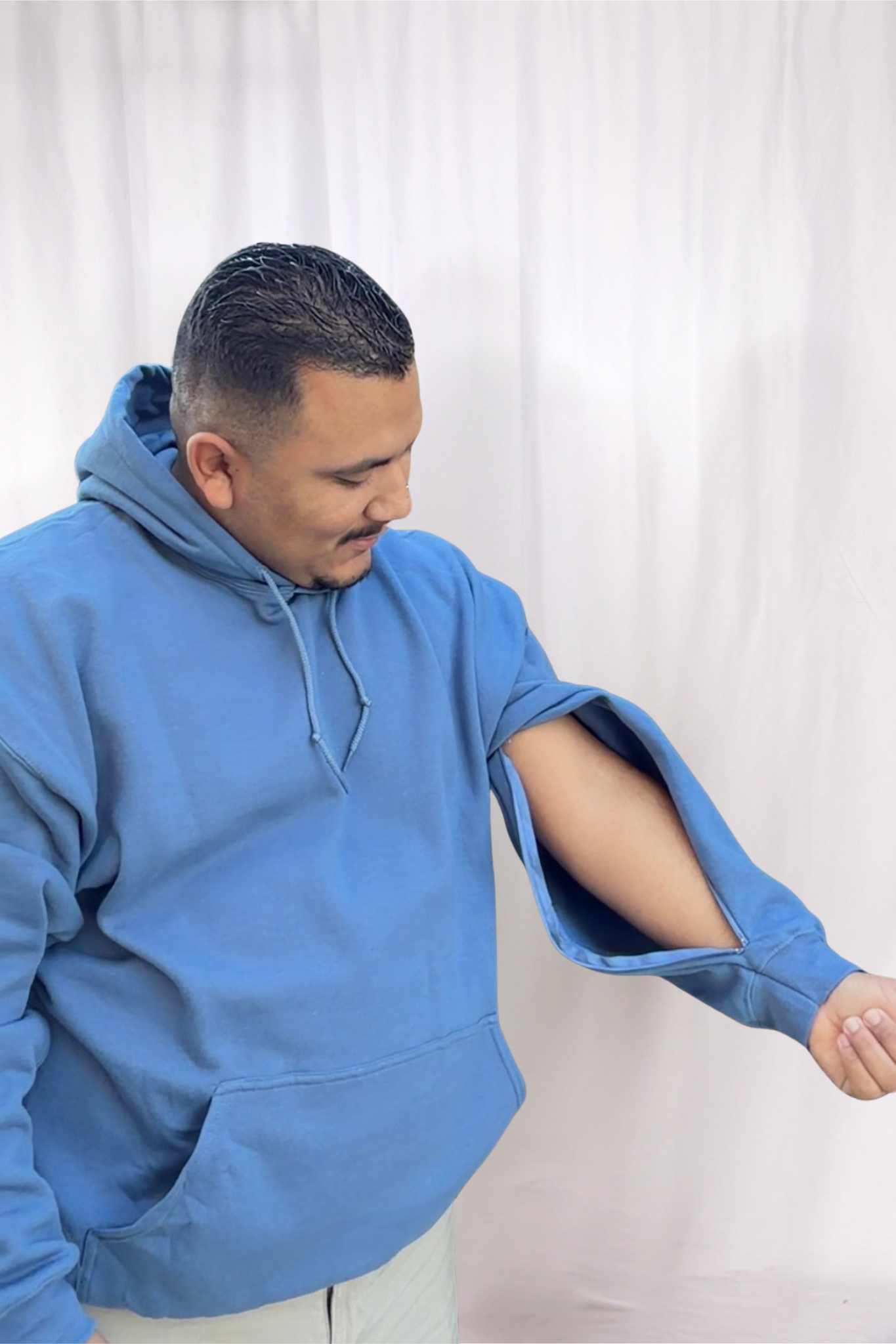 Man in blue hoodie showing his left arm with a large cut or injury.