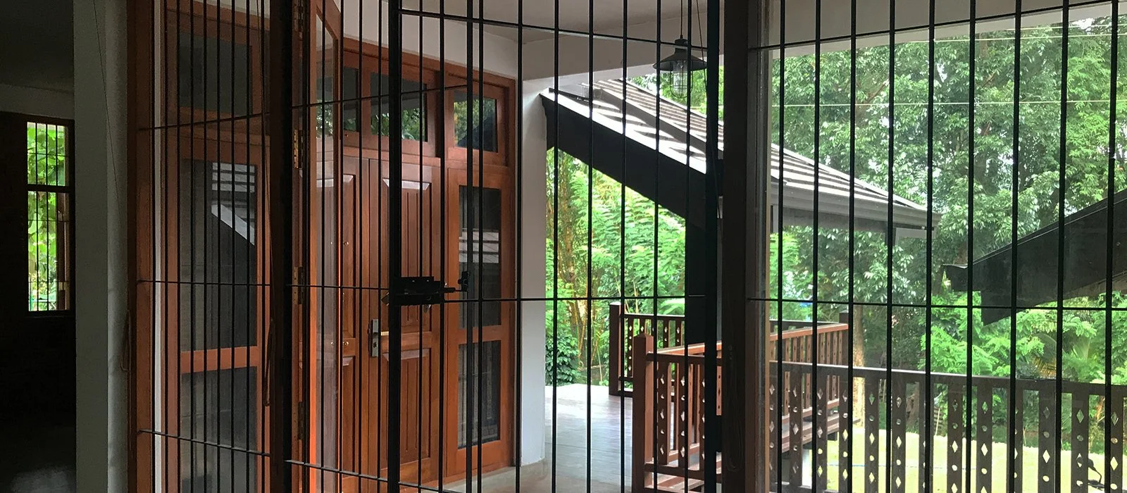 View of a wooden door and outdoor balcony through a metal security screen door.