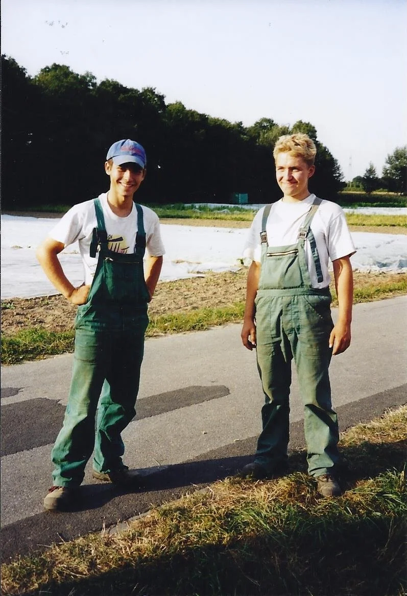 Zwei Jungen stehen auf einer Straße, im Hintergrund Felder und Bäume