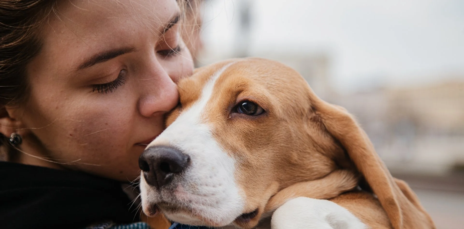 Donna che abbraccia un cane Beagle con espressione affettuosa.