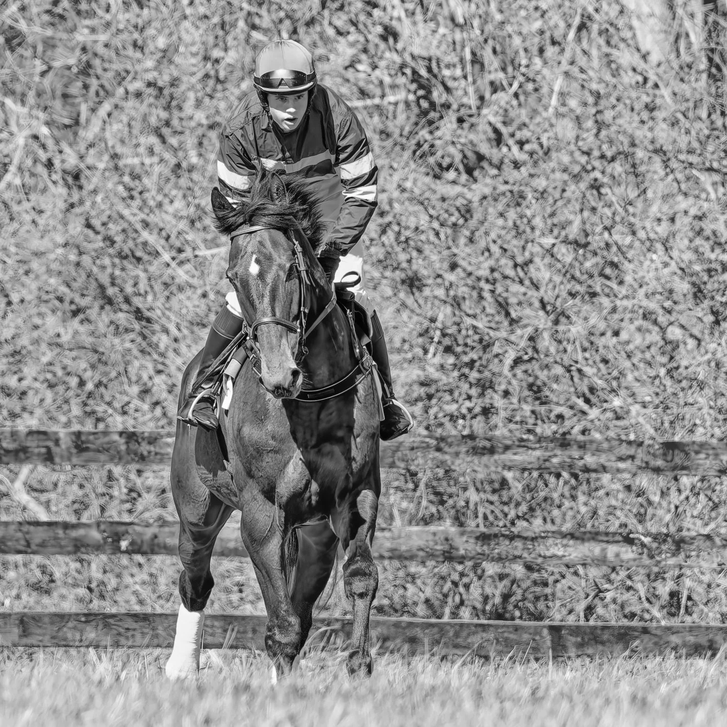 A person riding a horse in an outdoor area with trees in the background, black and white photo.