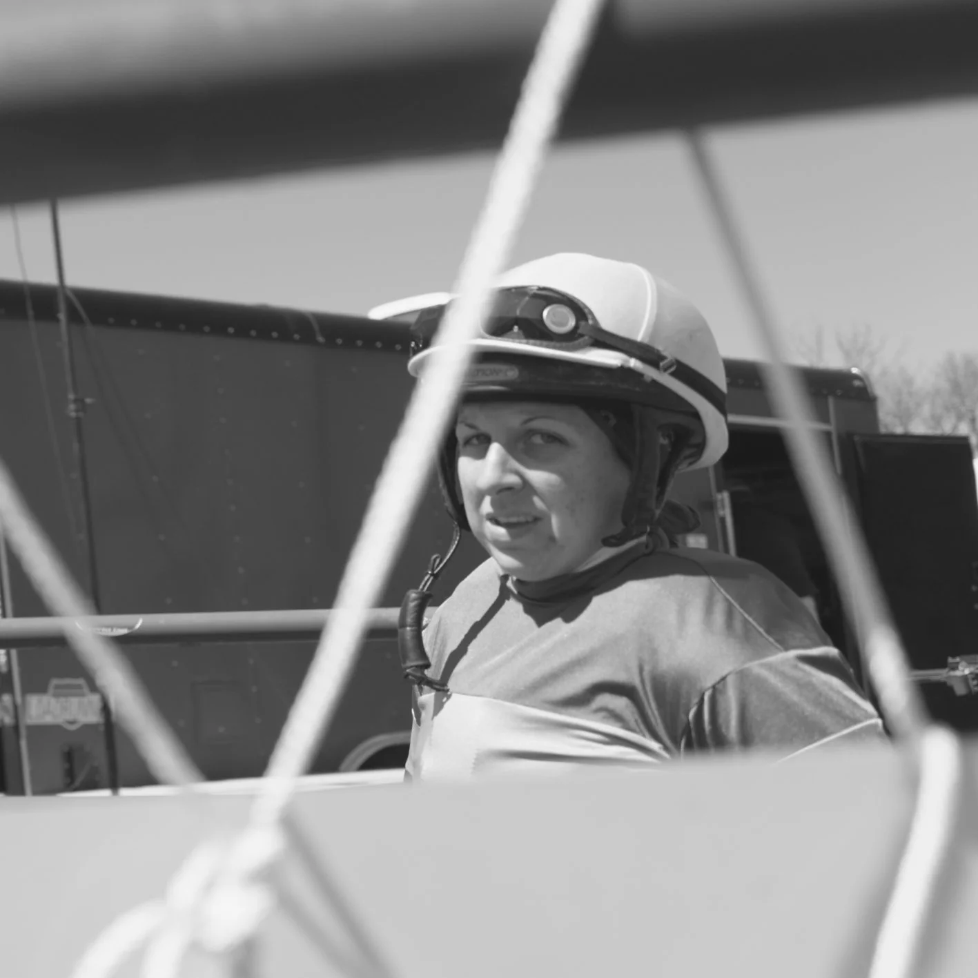 A person wearing a helmet sitting inside a small aircraft, looking towards the camera with a focused expression.