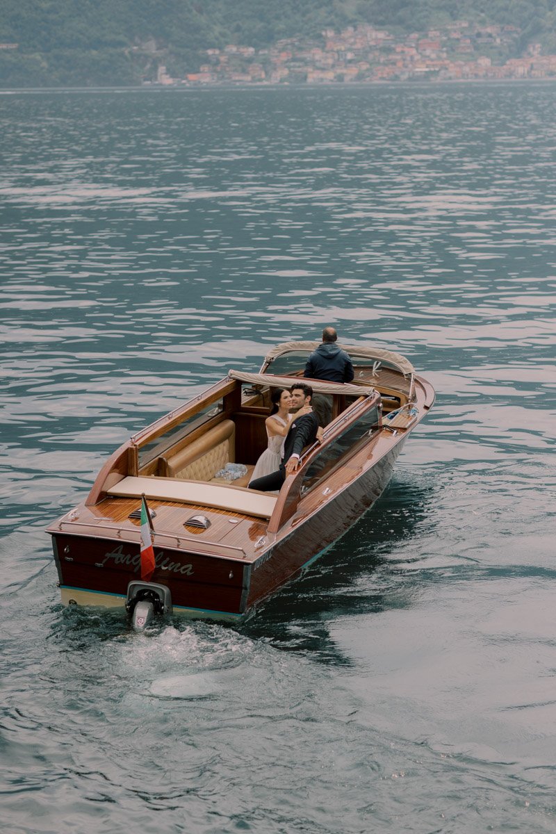 Explore the untouched beauty of Lake Como and the timeless sophistication of a wedding at the stunning Villa Balbiano with this captivating image. As the boat glides smoothly across the shimmering waters of the lake, the newlyweds are enveloped in th