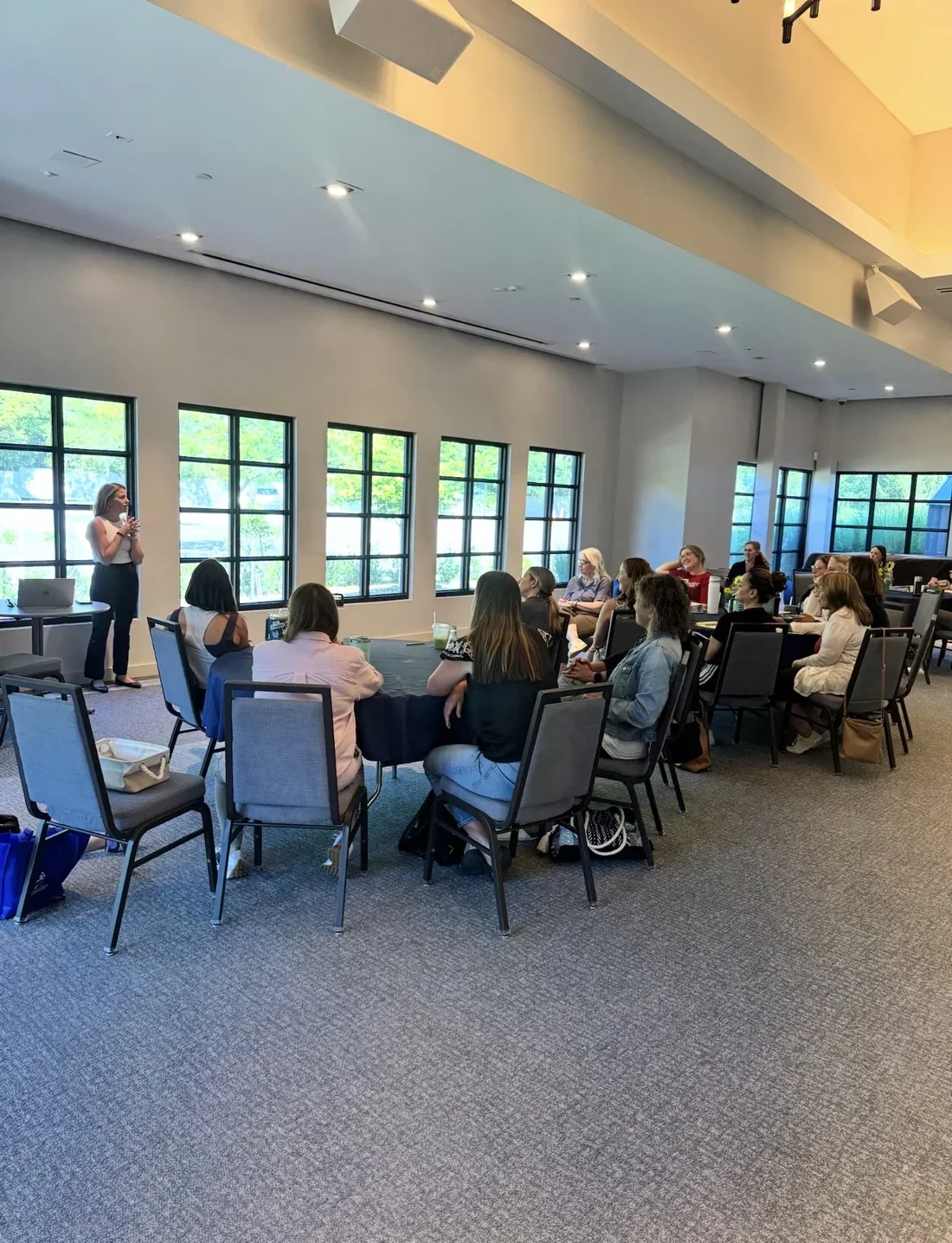 Mandy leading a workshop for a room of attendees seated at round tables