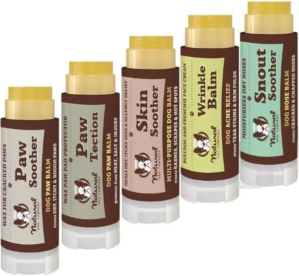 Five tubes of dog paw balm in different flavors including Paw Souther, Paw Temptation, Slip Soother, Wrinkle Balm, and Snout Souther, arranged in a row.