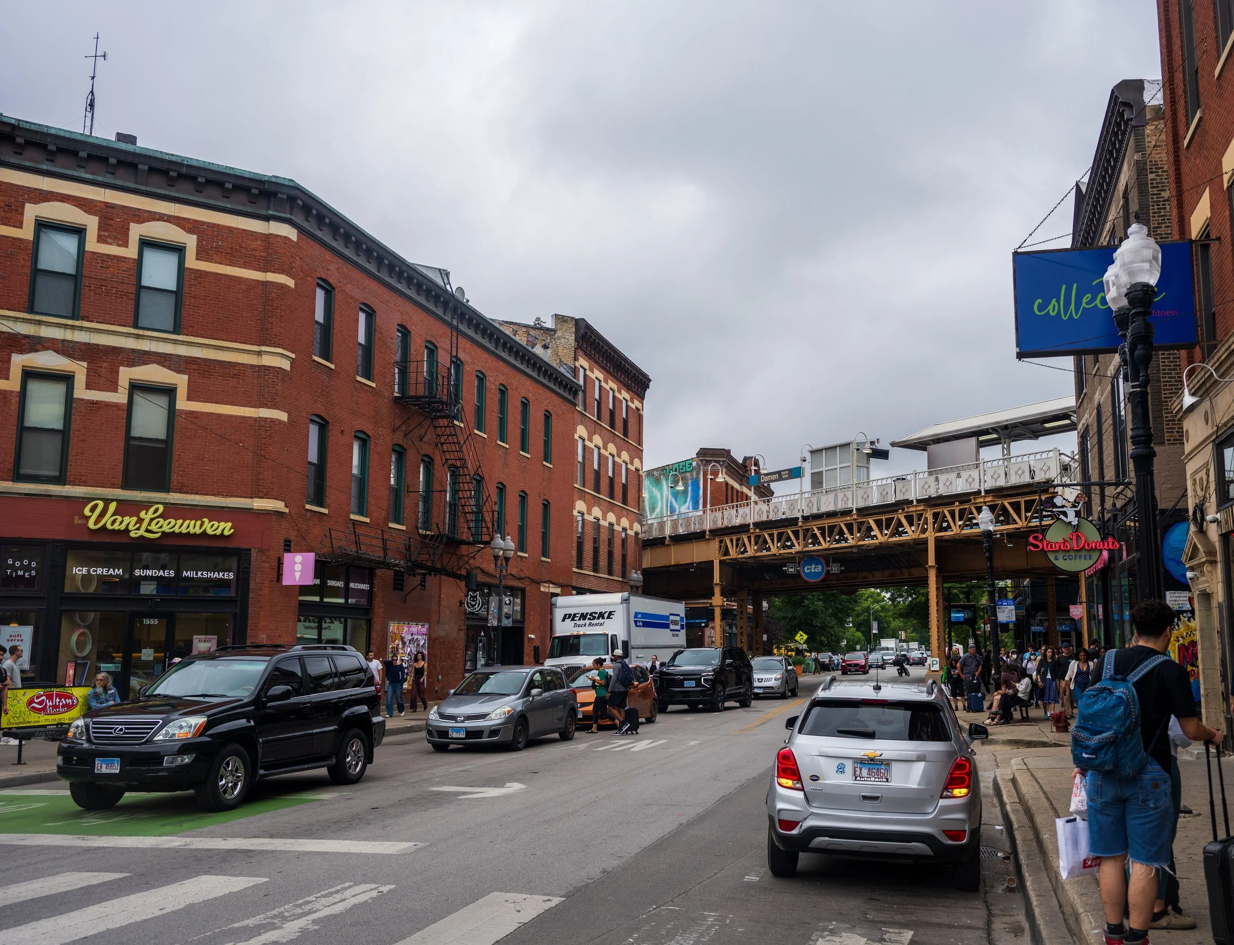 Chicago street with brick storefront buildings and an elevated train track overhead