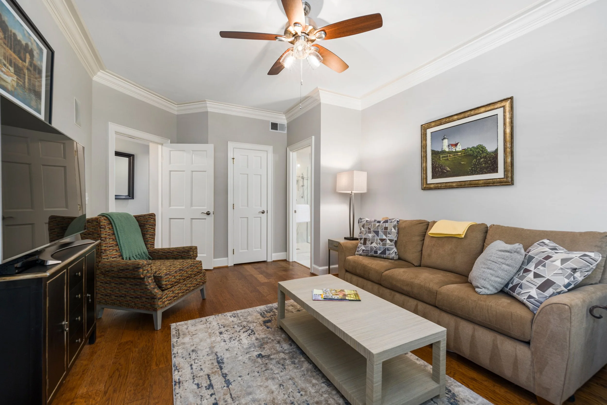 Furnished living room with a couch, an armchair, a coffee table, and a ceiling fan