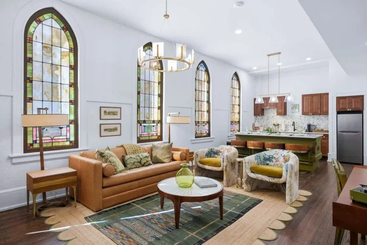 Apartment at The Raven with arched stained glass windows, a leather sofa, a round coffee table, and a kitchen along the back wall