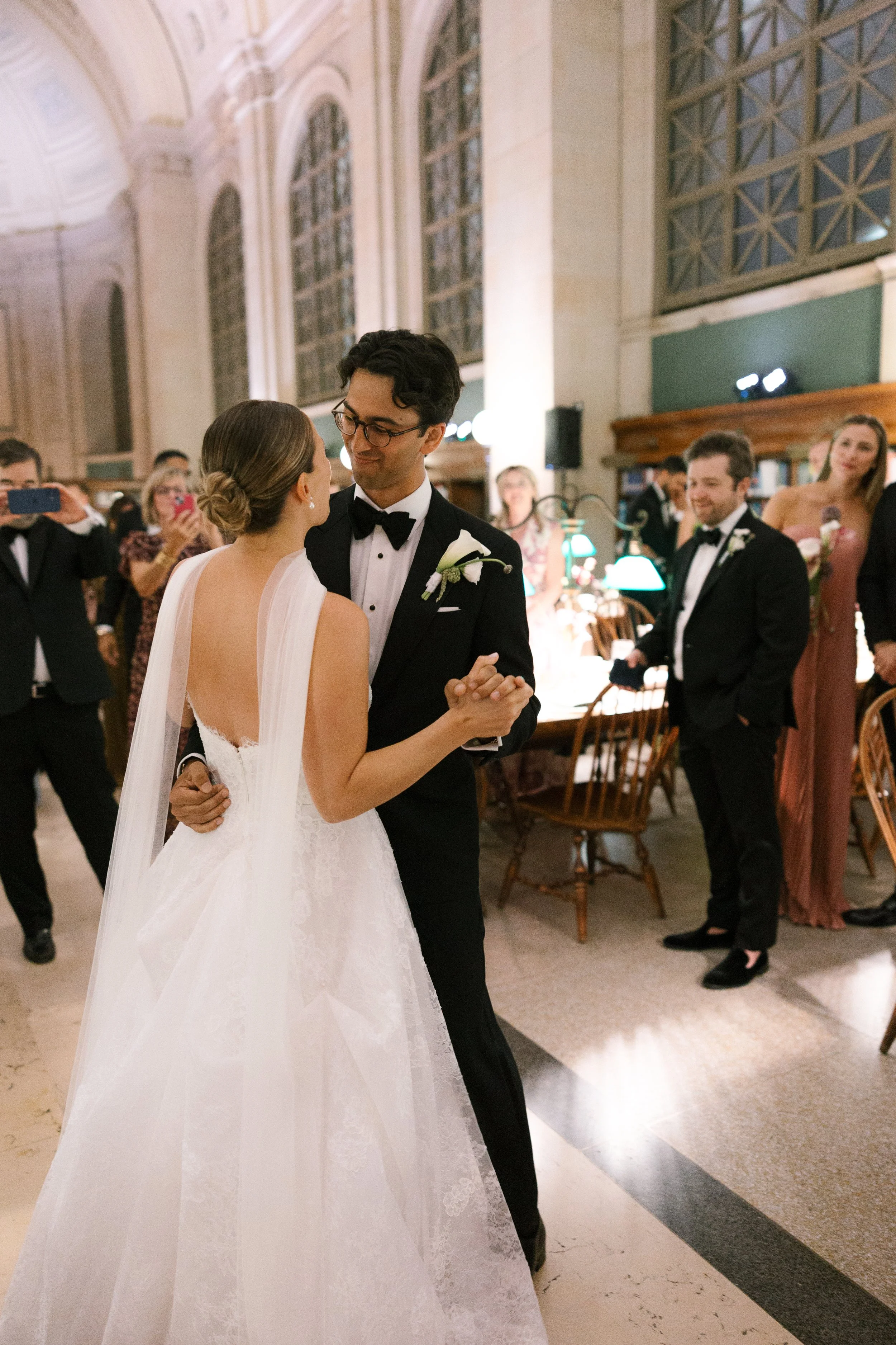 A bride and groom sharing a dance at their wedding reception, surrounded by guests.
