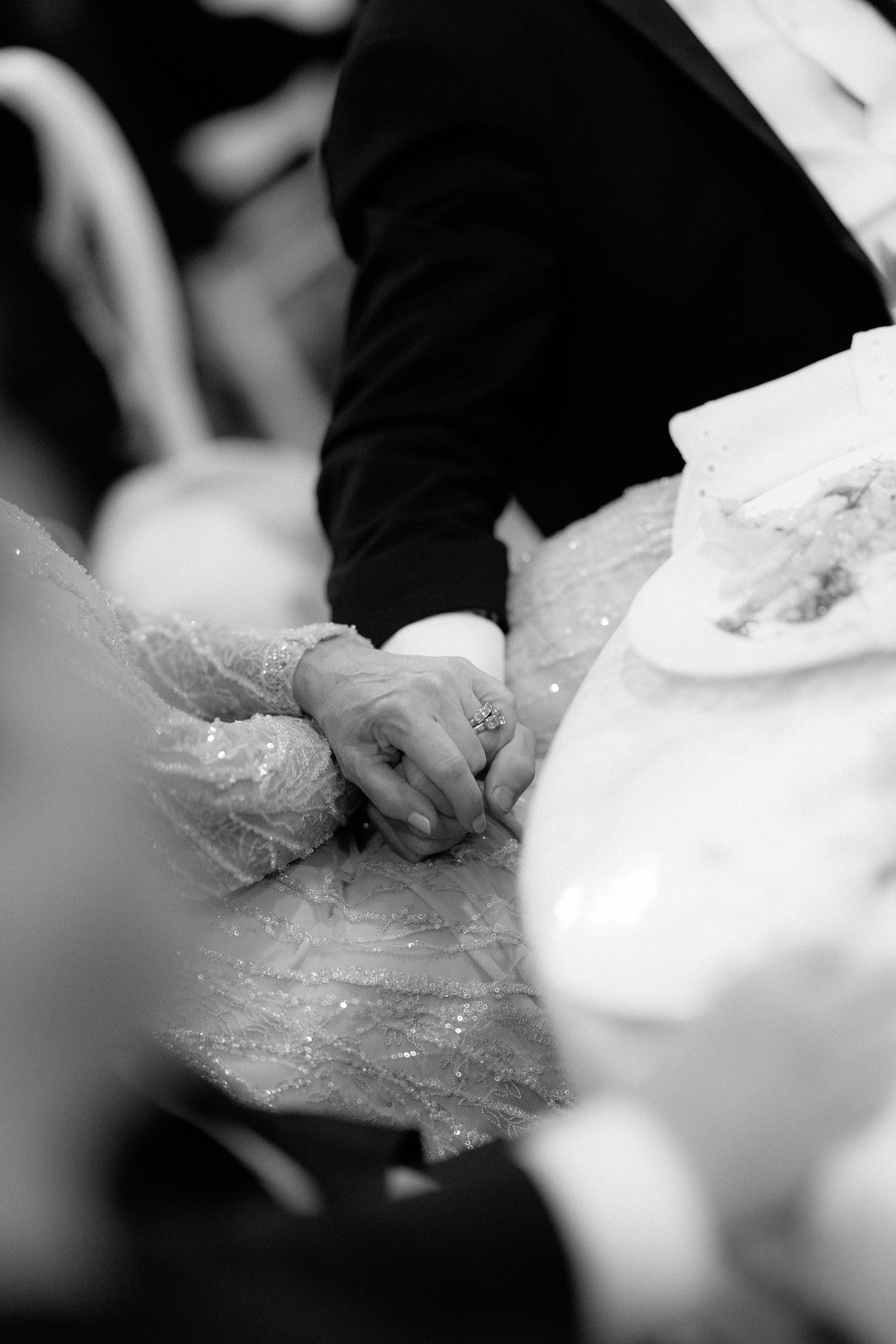 Close-up of a bride and groom holding hands at their wedding reception.