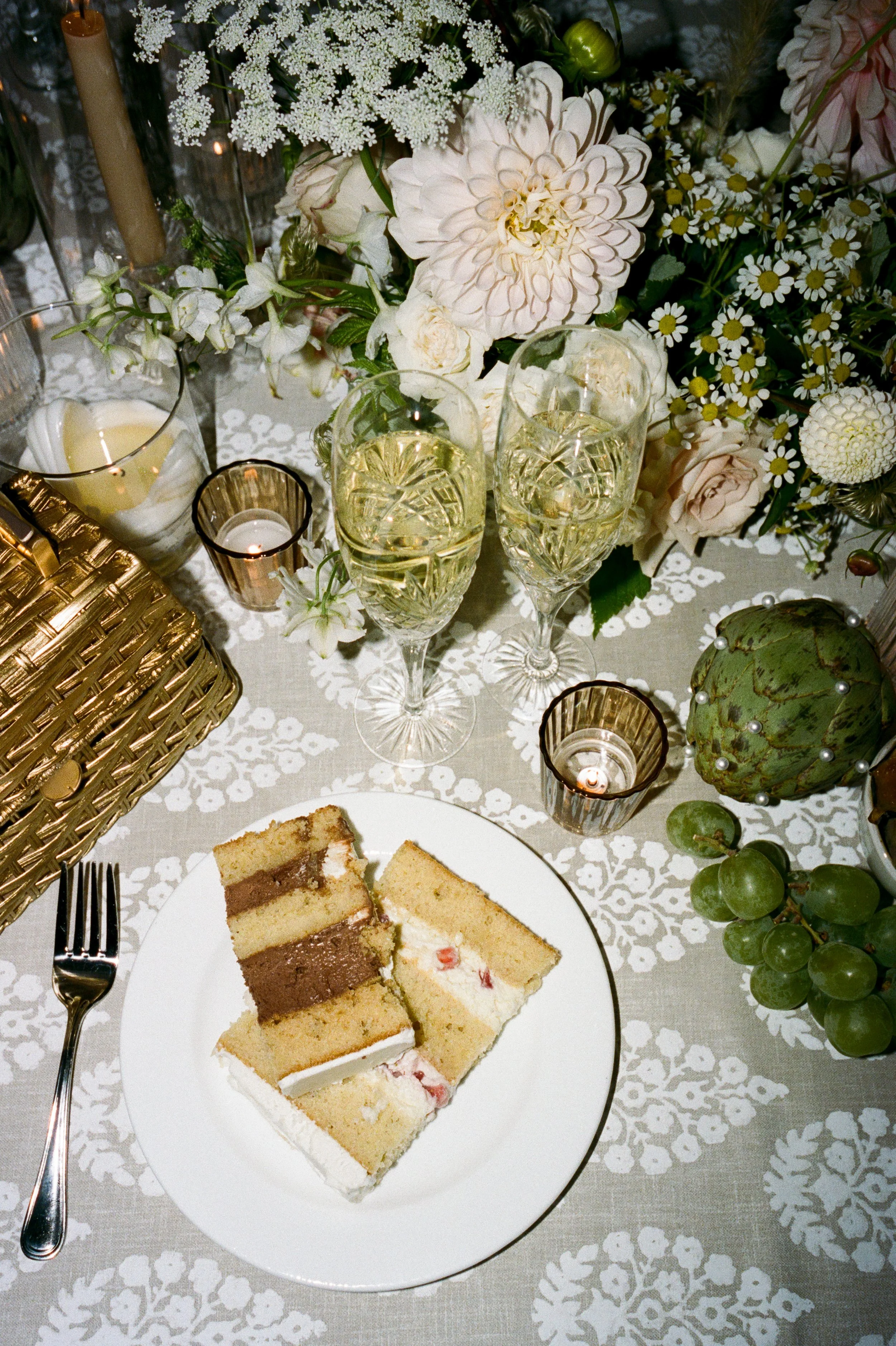 A table set with floral decorations, white cake slices, champagne glasses, candles, and other decorative items.