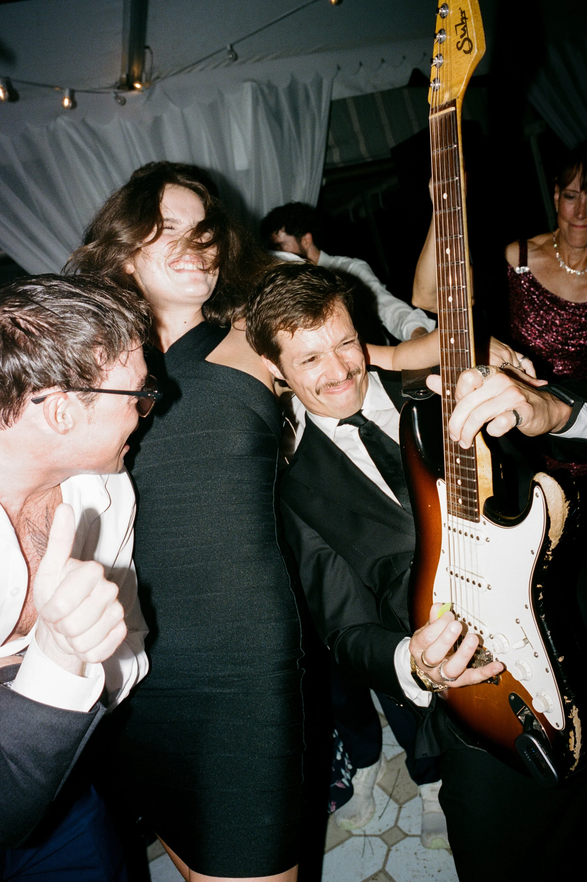 People dancing and enjoying a party, with a man playing an electric guitar.