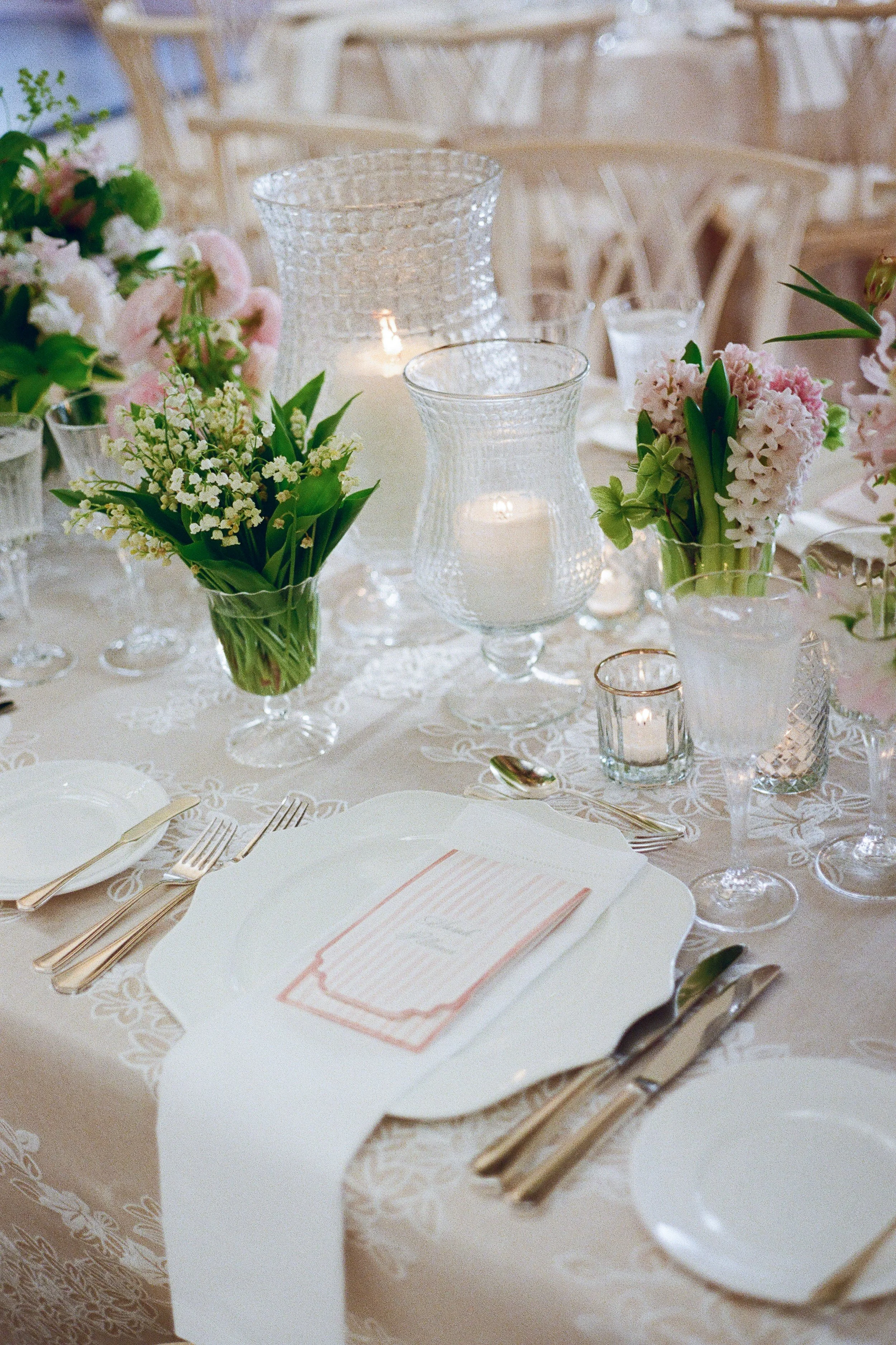 Elegant table setting with floral centerpieces, candles, and formal dinnerware for a wedding or special event.