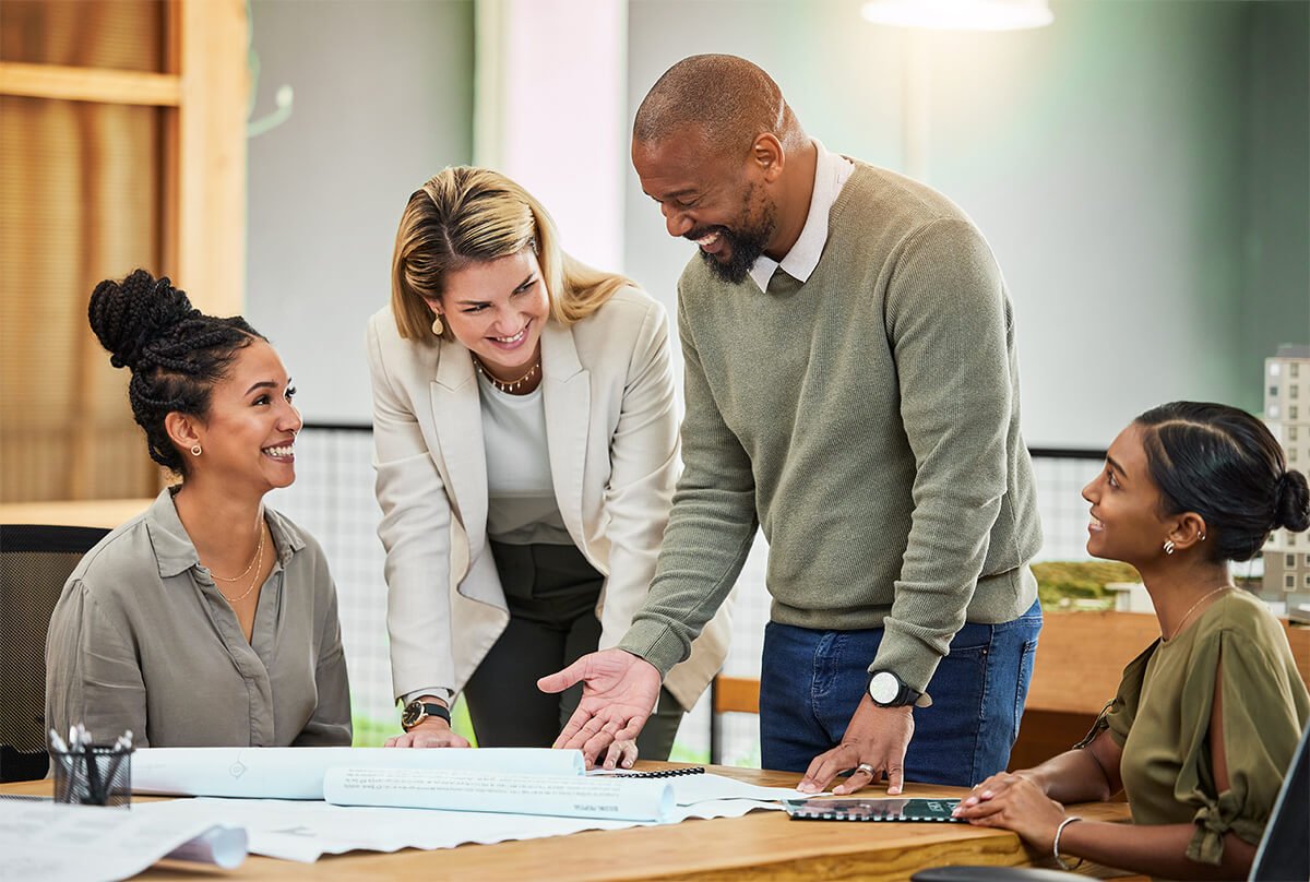 Équipe de collègues souriants travaillants autour d'une table.