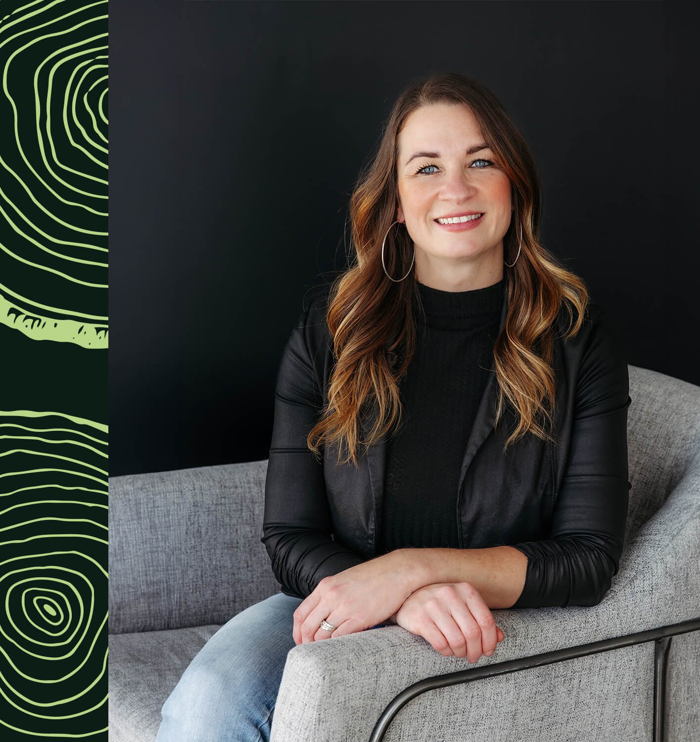Mélinda Roy souriante portant une veste en cuir noir et un jean bleu clair, assise sur un canapé gris devant un fond noir avec des motifs verts à gauche.