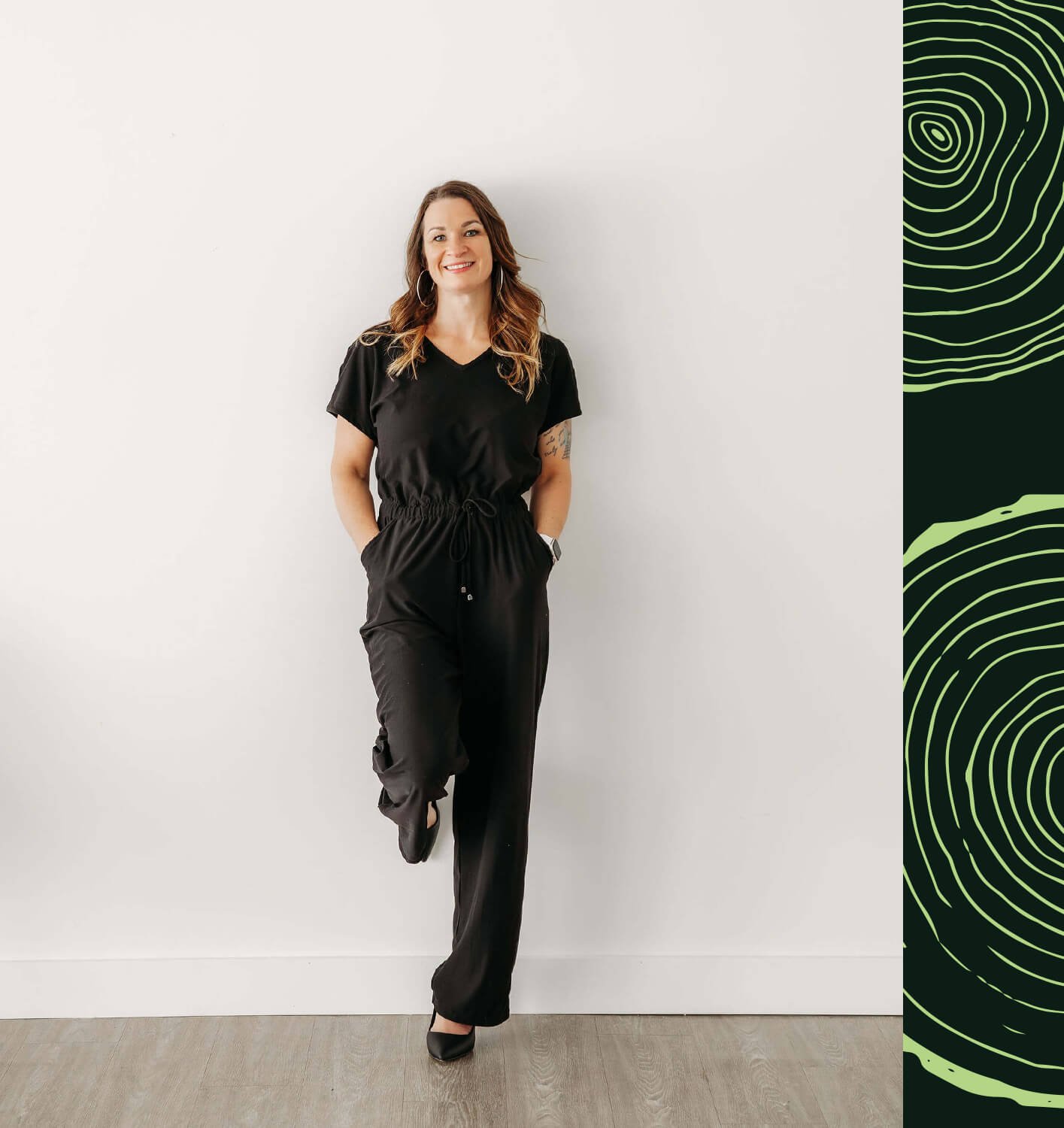 Mélinda Roy, CRHA souriante, habillée en noir, pose décontractée contre un mur blanc.