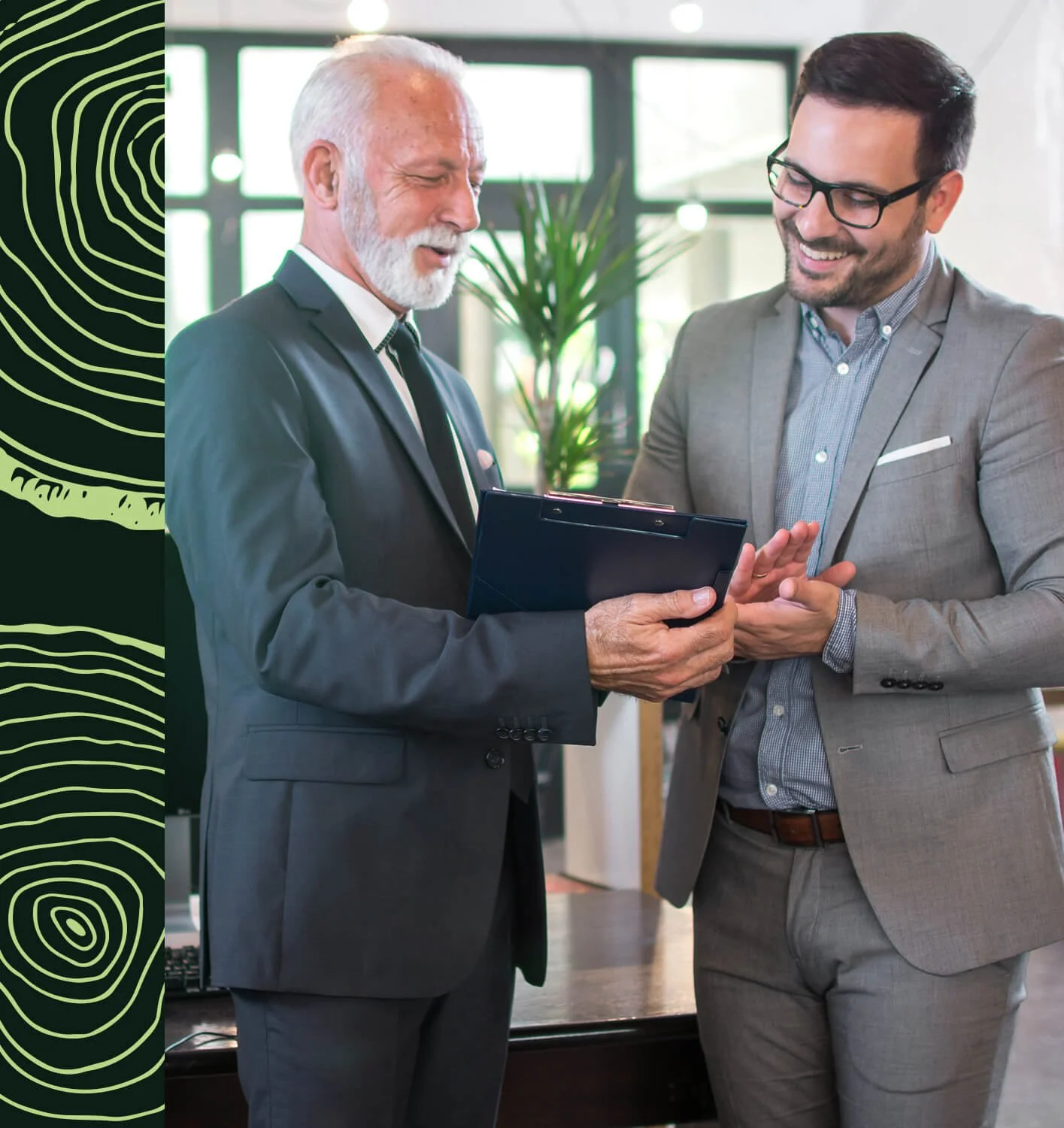 Deux hommes d'affaires discutent dans un bureau moderne, regardant un carnet . L'un porte un costume sombre avec une cravate, l'autre un costume gris avec des lunettes. Ambiance professionnelle et convivialité.