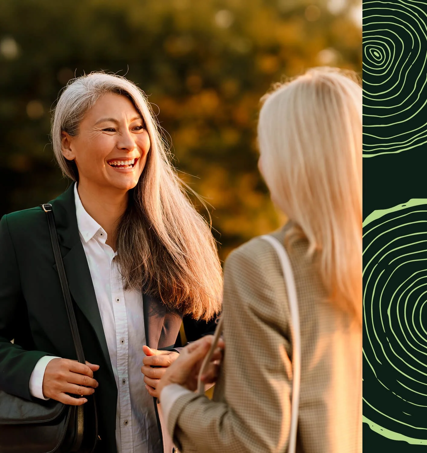 Deux femmes discutent en extérieur, l'une souriante, l'autre vue de dos, dans un parc en automne.