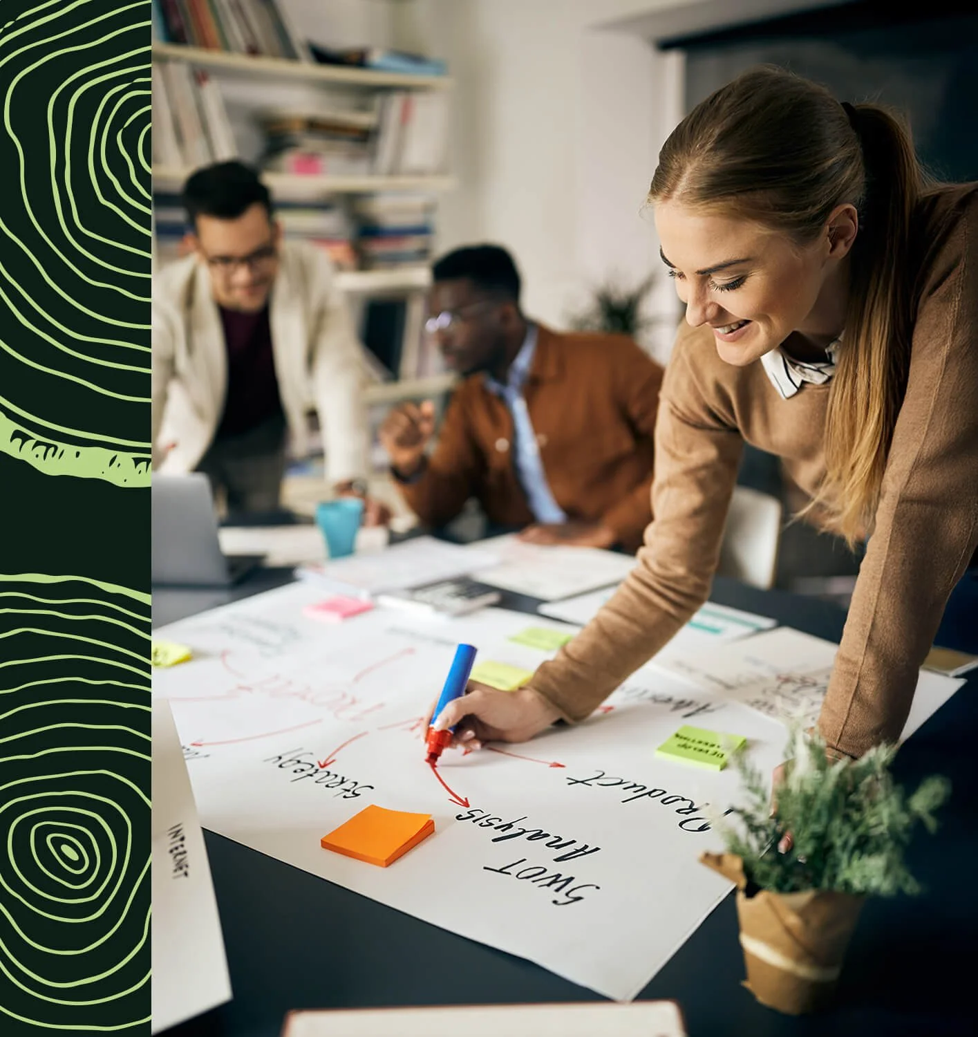 Une jeune femme en train de dessiner et réaliser une analyse SWOT sur une table, entourée de collègues dans un bureau.
