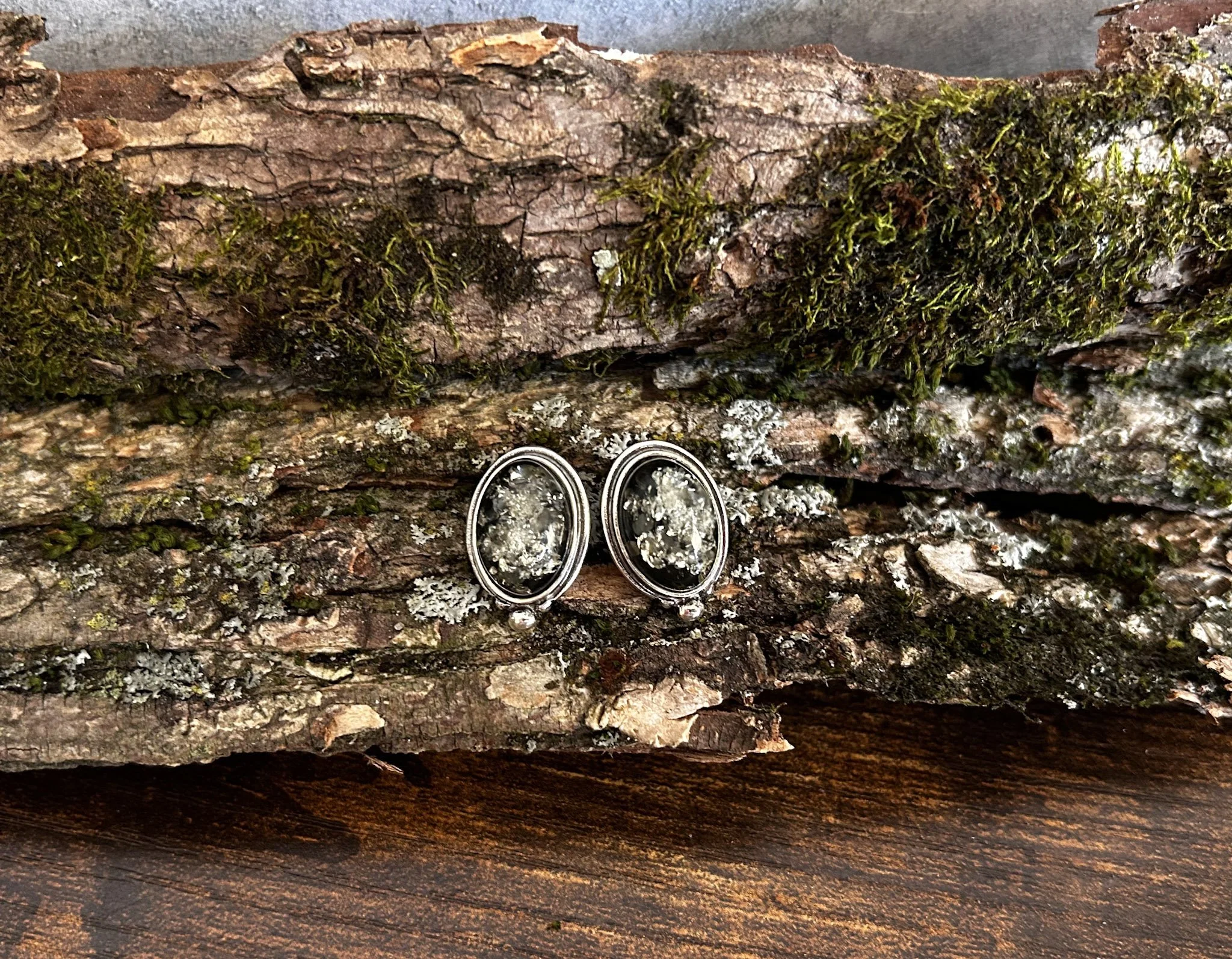 Silver stud earrings in oval shape with green amber