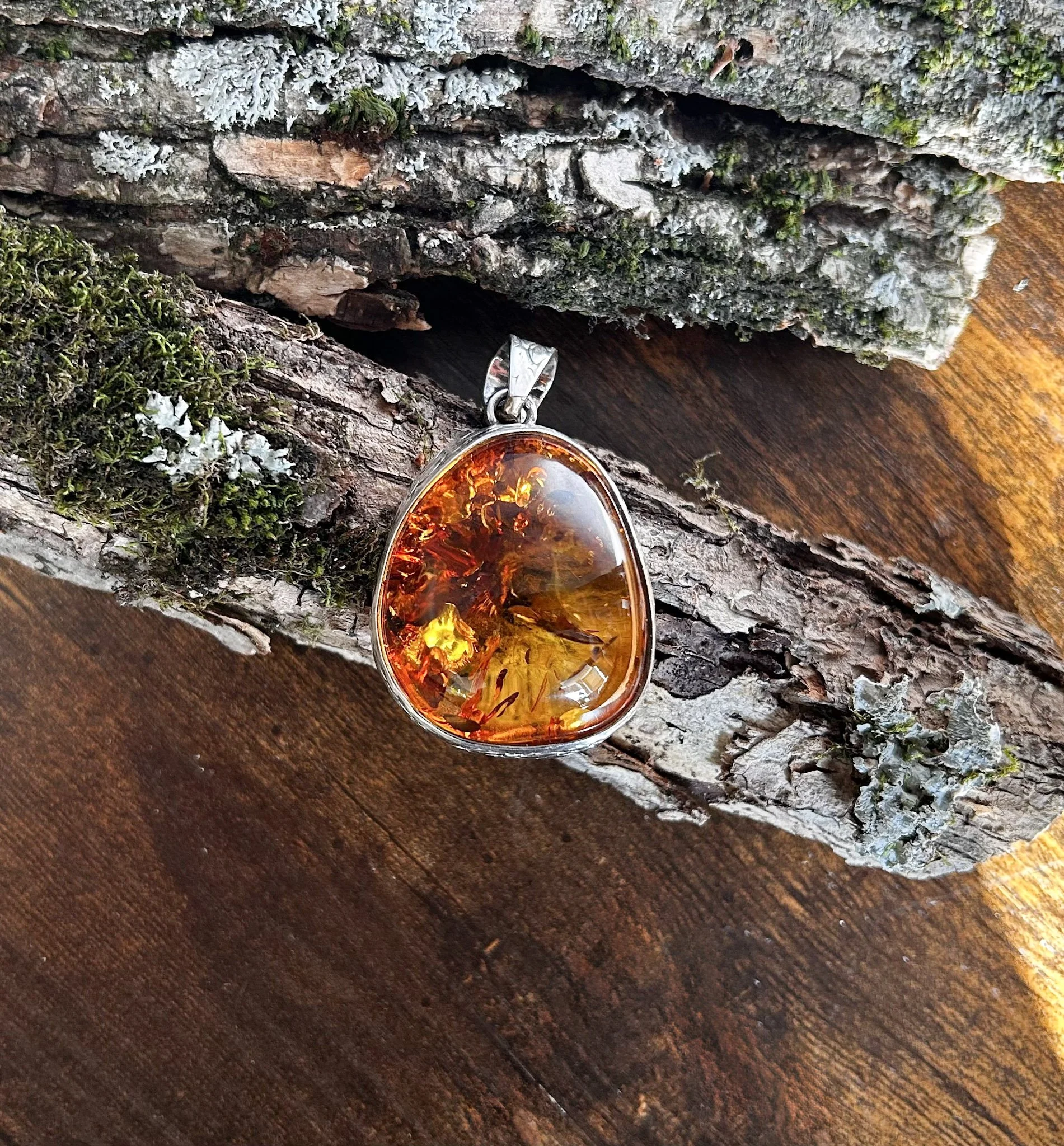 Pear shaped cognac colored Baltic amber pendant adorned in silver