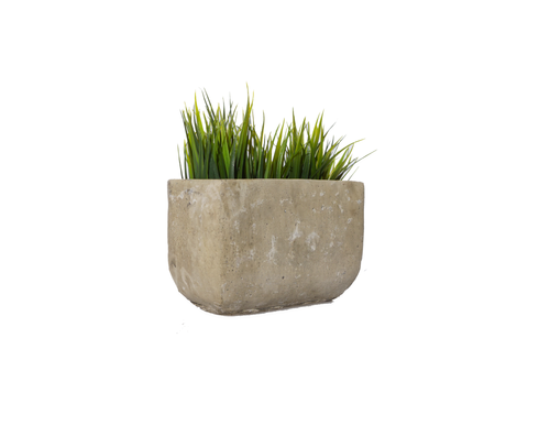 A rectangular concrete planter with green grass growing inside.