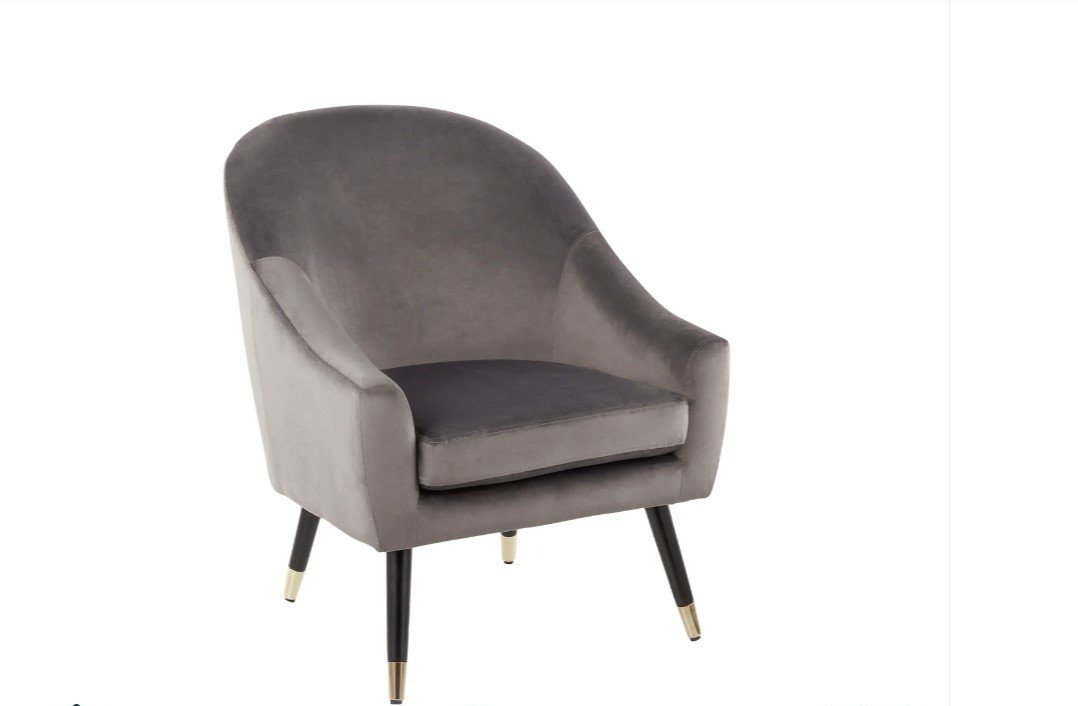 A gray velvet armchair with black and gold tapered legs.