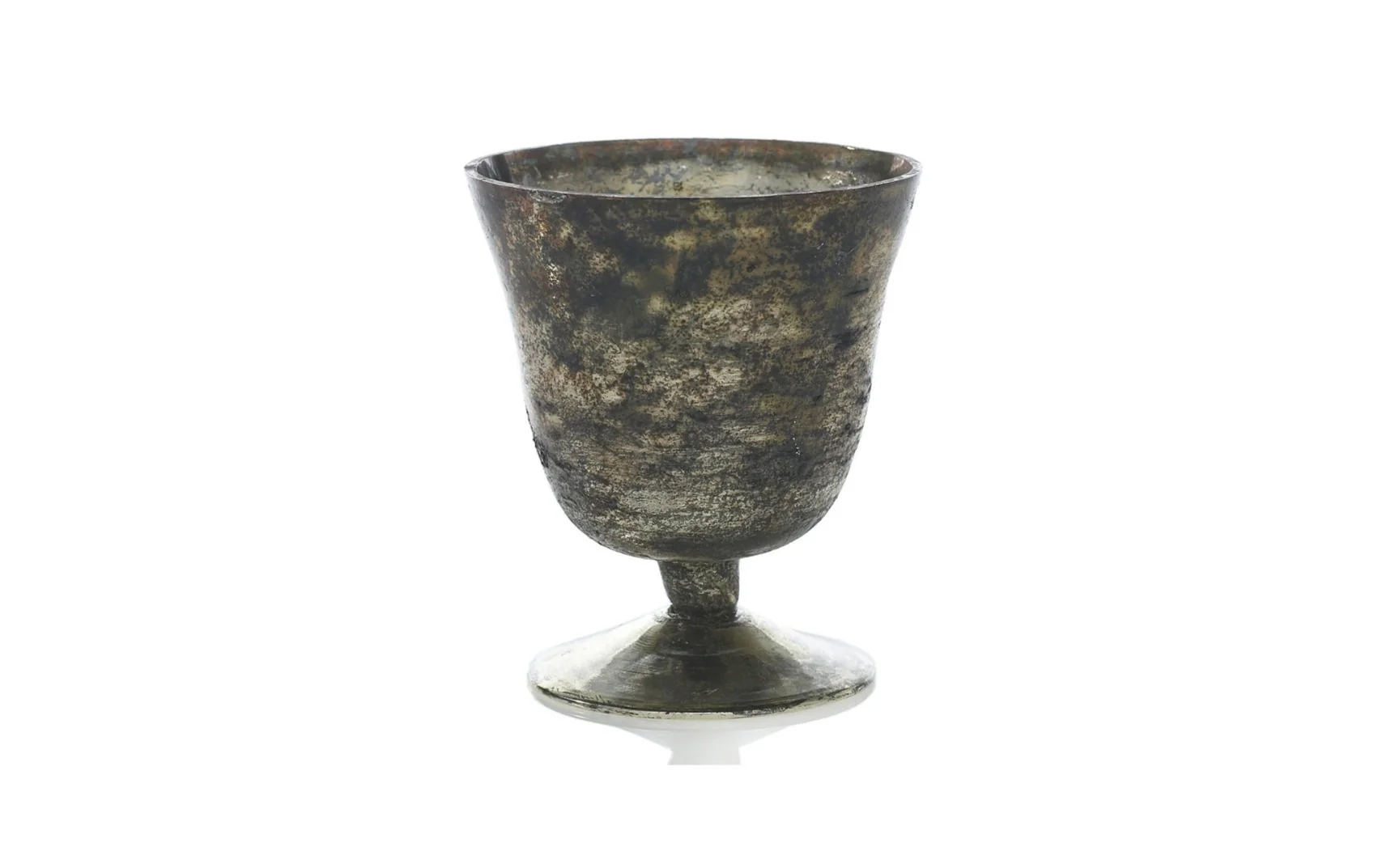 Ancient metallic goblet with a dark, mottled surface and a stemmed base, isolated on a white background.