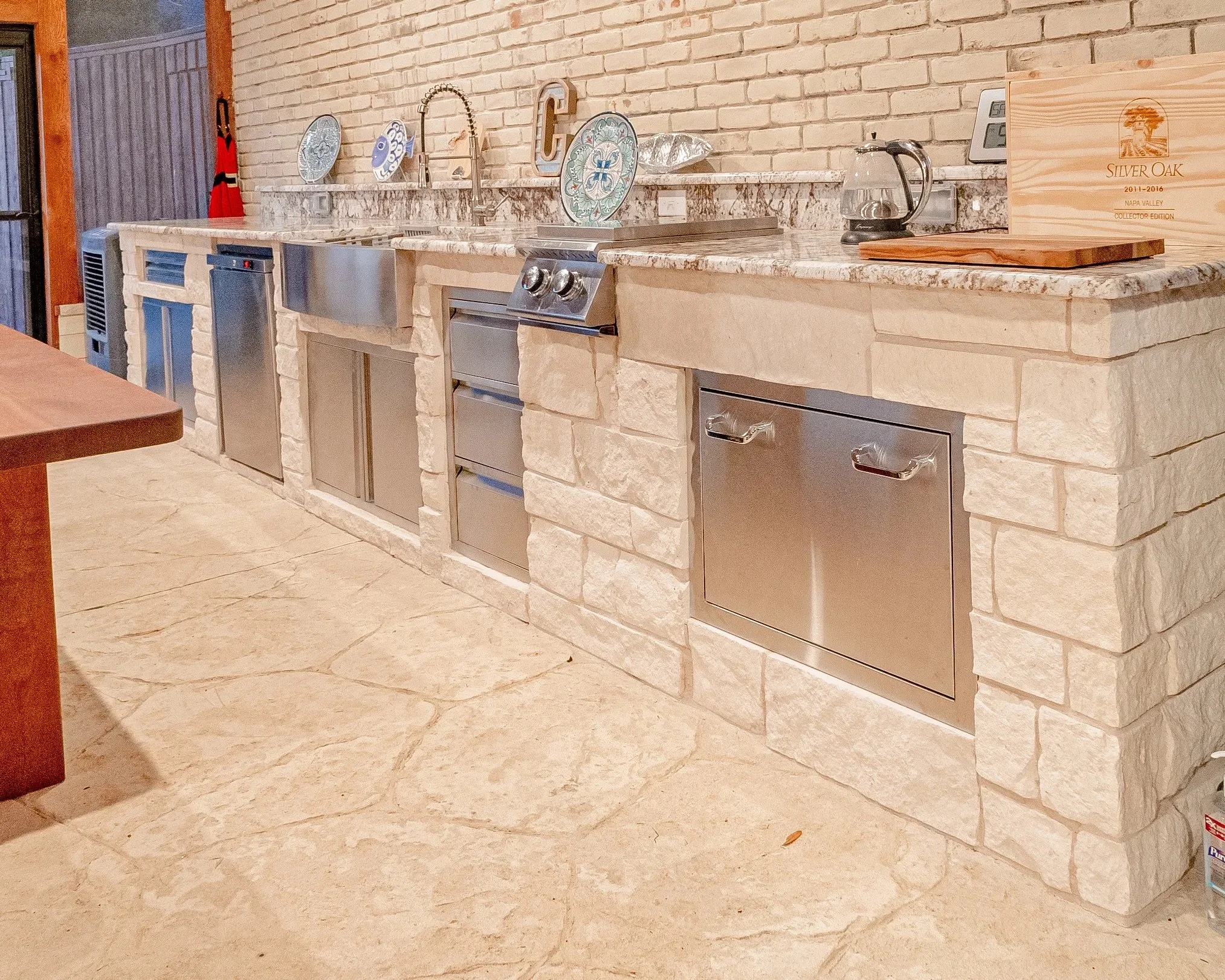 Kitchen with stone facade, marble countertop, stainless steel appliances, and decorative plates and utensils.