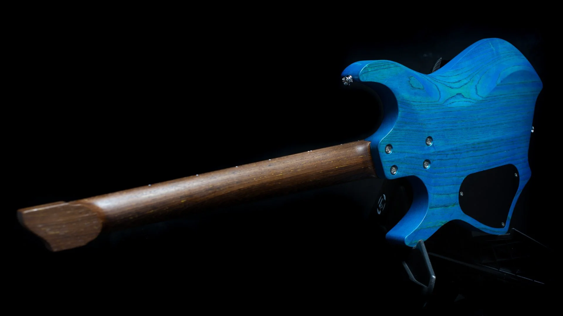 Back view of a blue stained headless - multiscale electric guitar focusing on the african wenge neck
