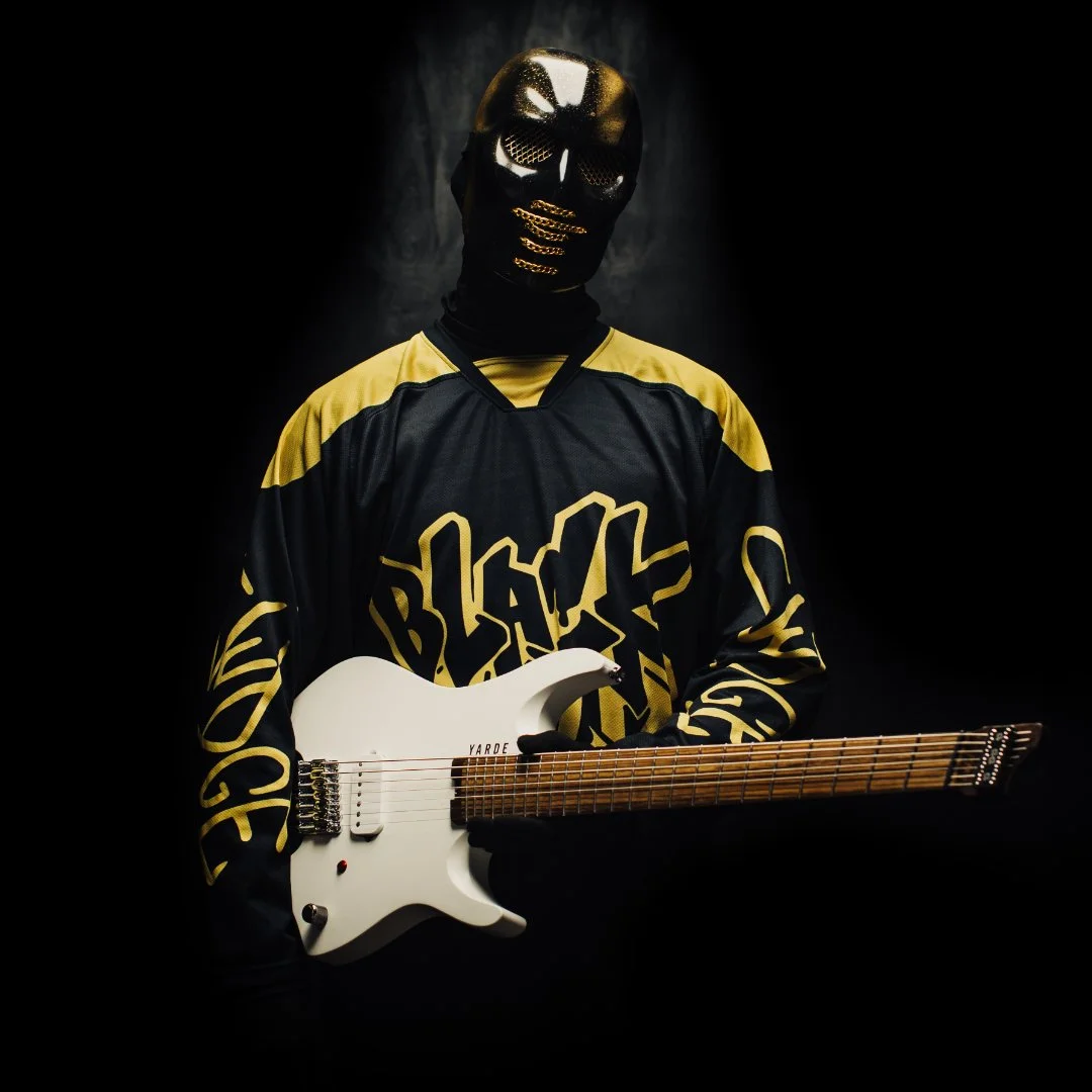BLACKGOLD's 'JUDGE' holding a white 7 string headless multiscale electric guitar