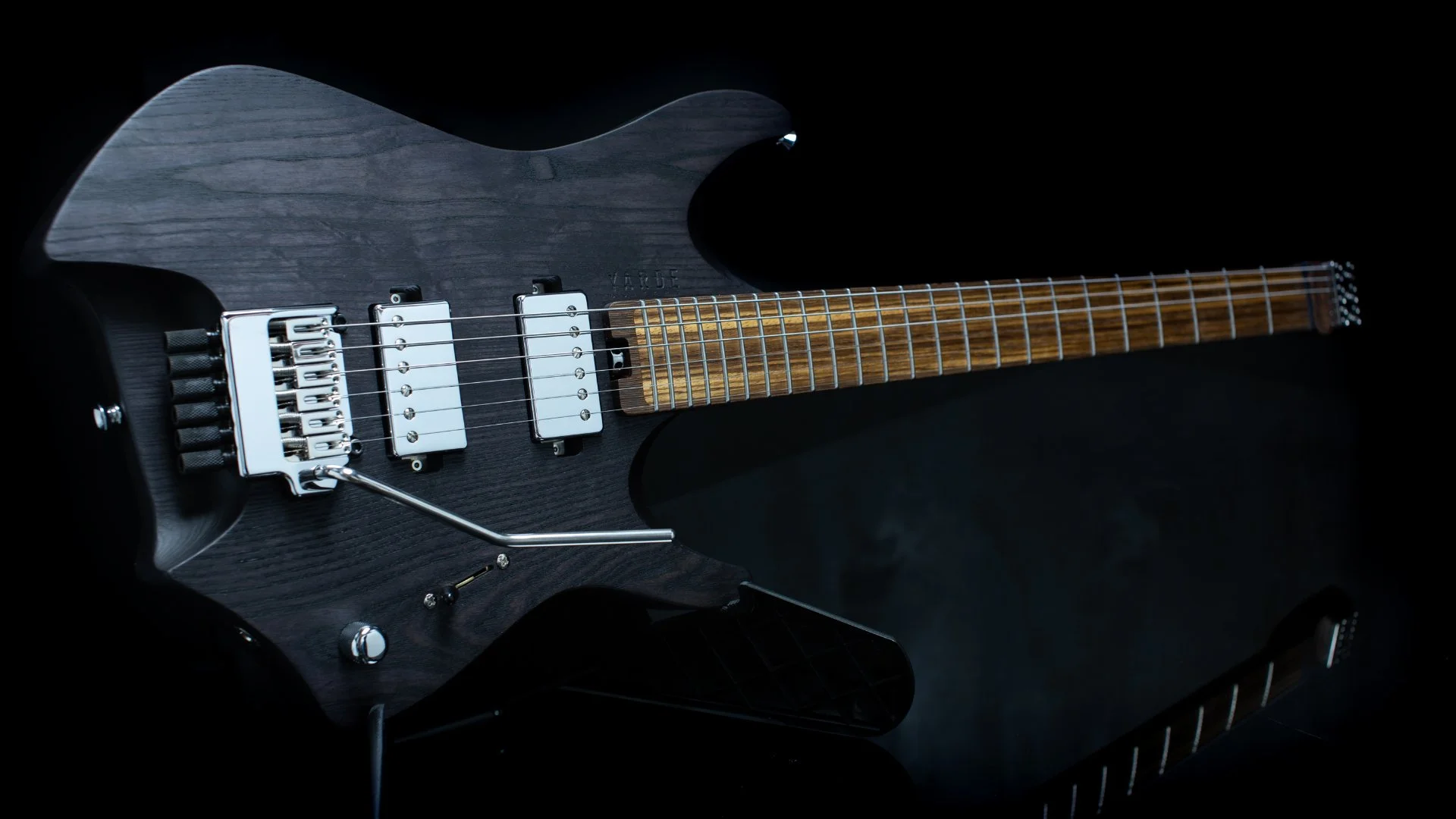 A headless electric guitar with black stain finish and chrome tremolo bridge - landscape front view
