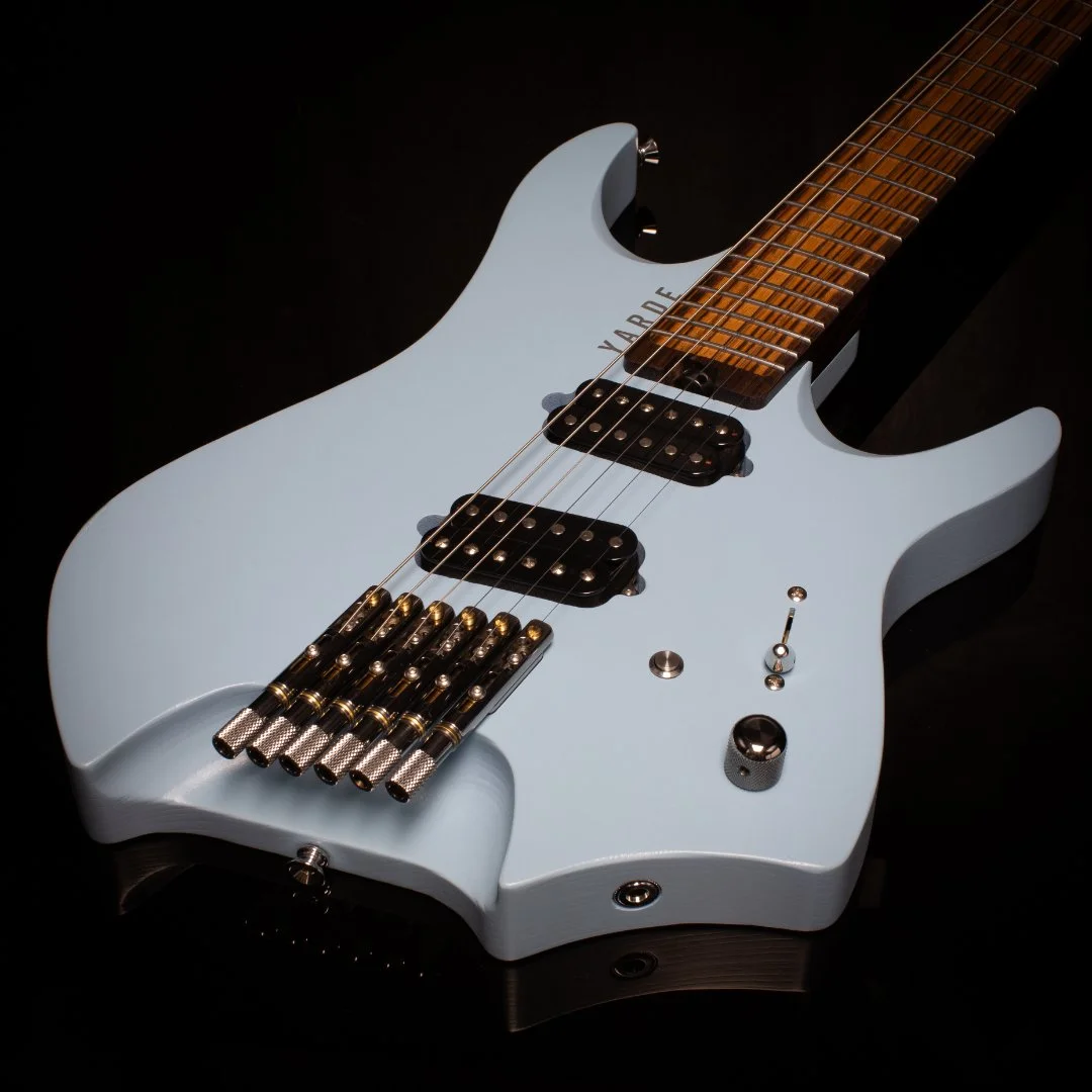 A light blue headless - multiscale electric guitar with a black background, featuring custom angled pickups and chrome hardware - 3/4 view of body