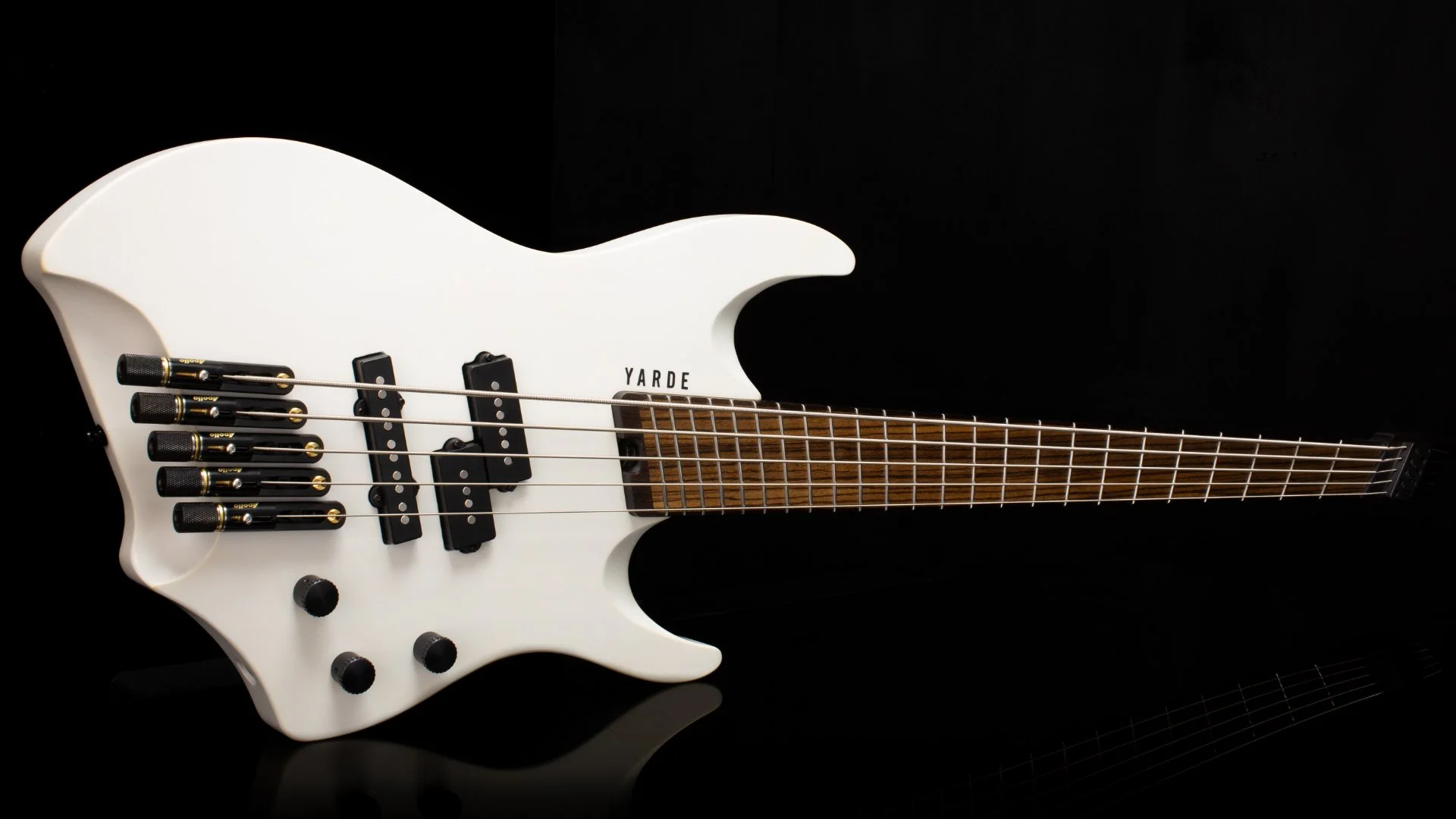 A white 5 string headless - multiscale bass with black hardware laying on its' side