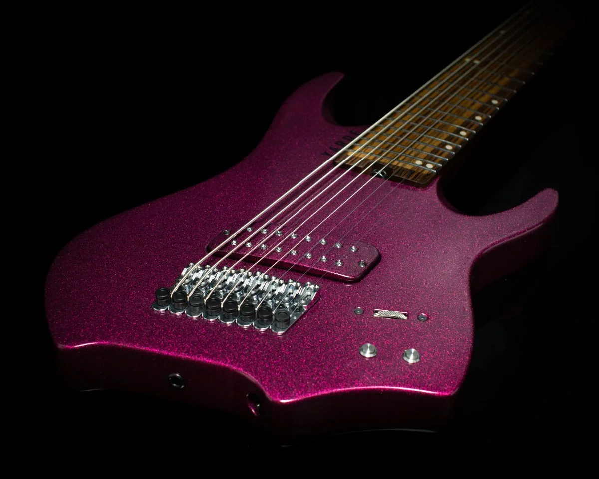 Body focussed view of a 8 string headless - multiscale elctric guitar with chrome hardware and matching painted pickup cover