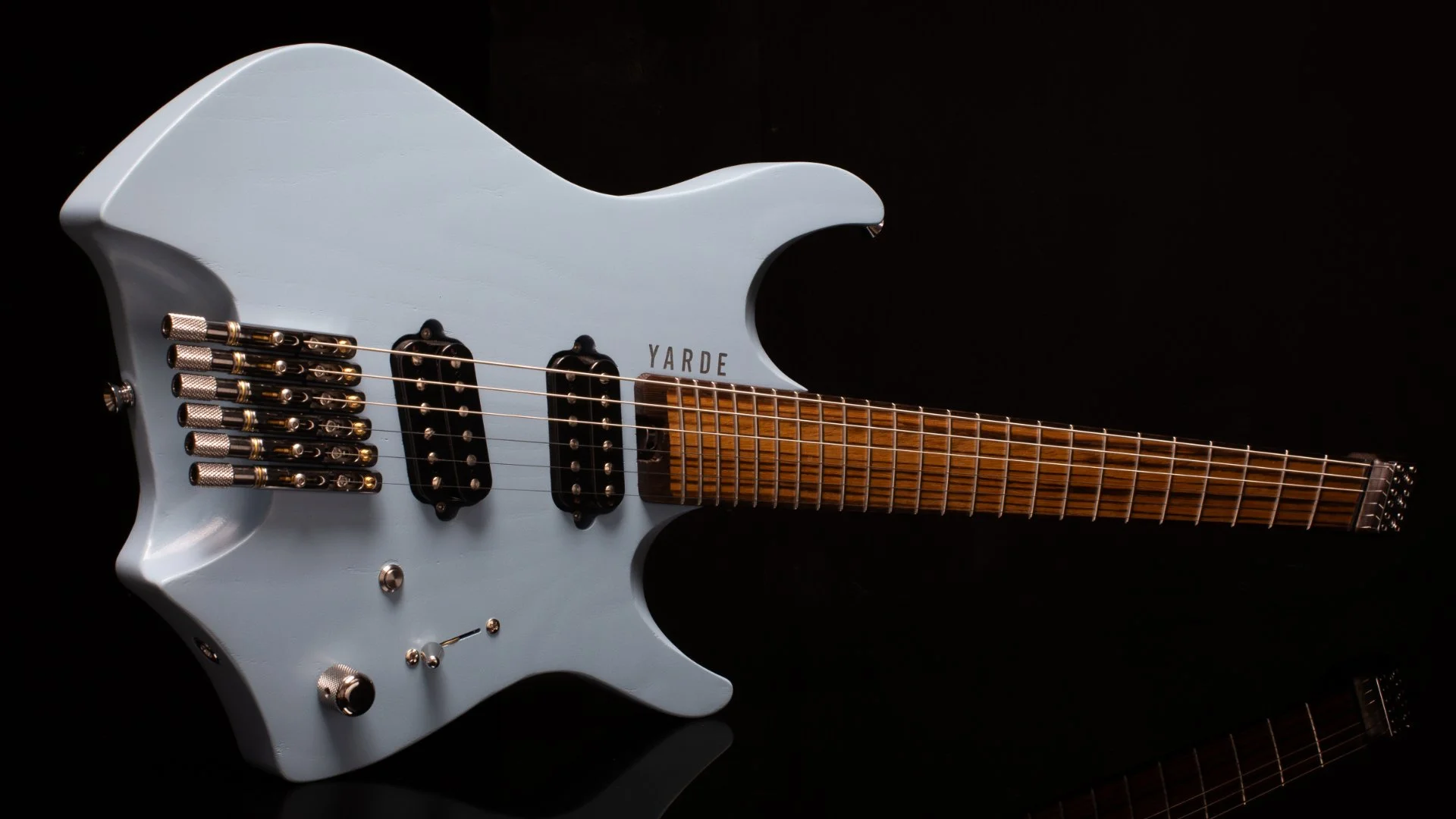 A light blue headless - multiscale electric guitar with custom pickups and a black background - Landscape view