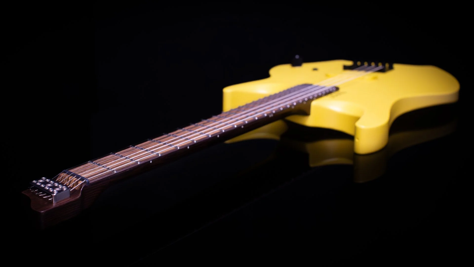 Close-up of a bright yellow painted headless - multiscale electric guitar with an inlaid zebrano fretboard with a black fixed bridge against a dark background - Neck and headstock view